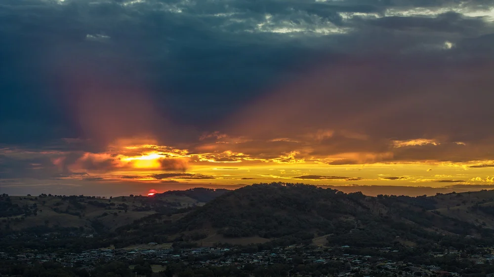 Sunset over hills with dramatic clouds and vibrant sky