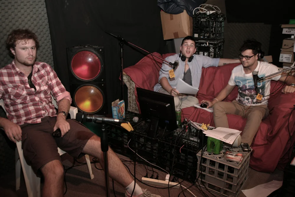 Podcasters in studio with microphones, wires, and audio equipment.