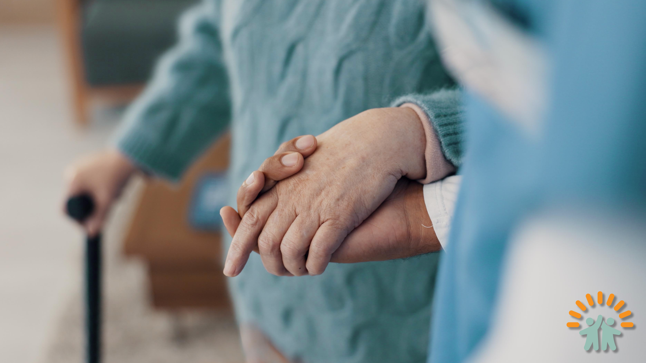Close-up of elderly person holding hands with caregiver, one using a cane, in a supportive gesture.
