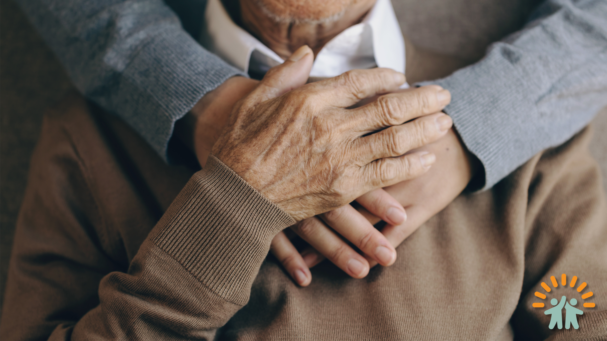 Close-up of elderly hands gently placed on each other, resting on a person's shoulder, conveying care and support.