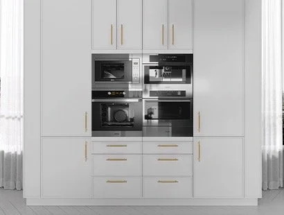 White kitchen cabinet wall with built-in black and stainless steel microwave, oven, and coffee machine, with gold handles.