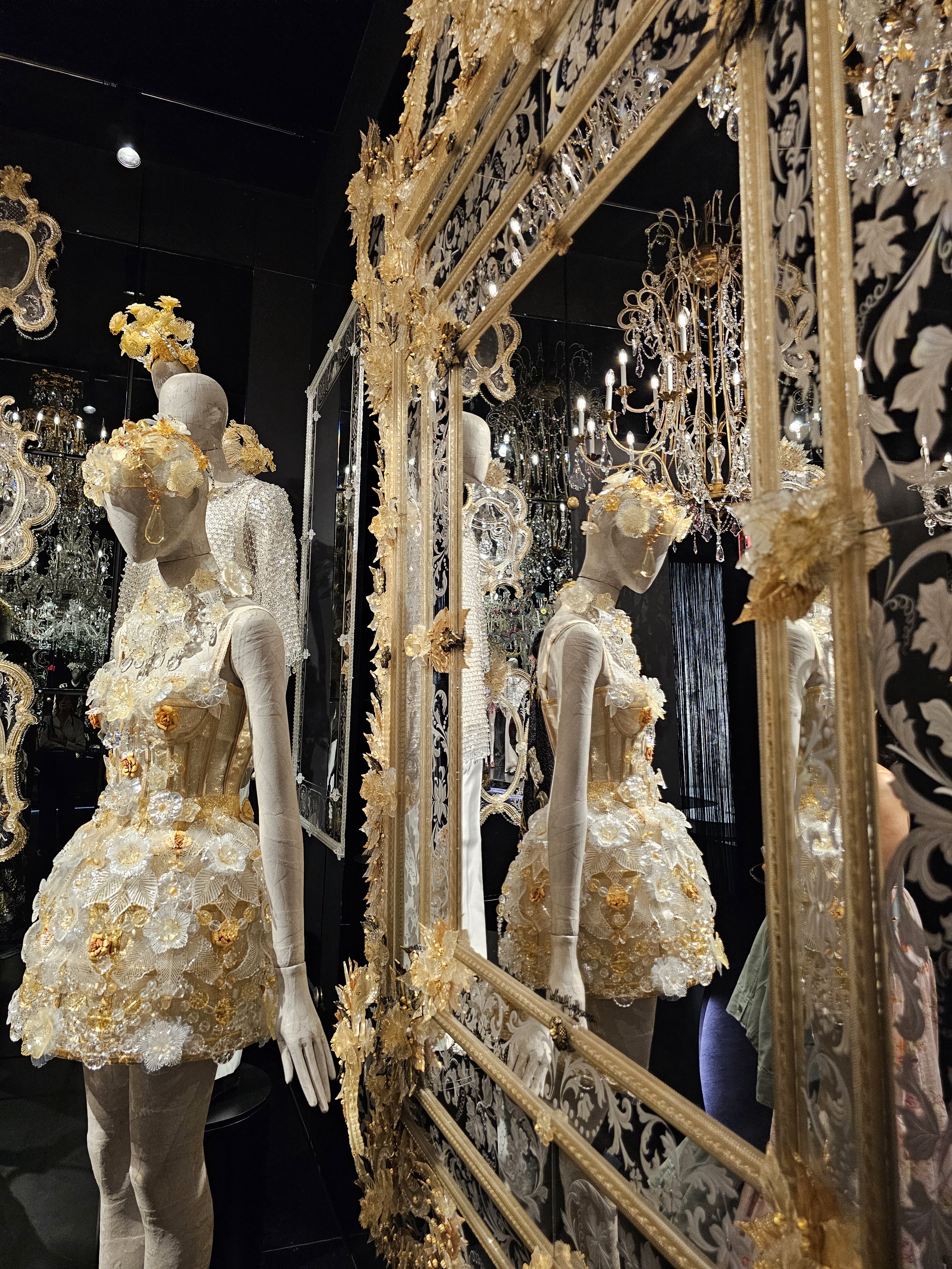 a gold and white dress on a mannequin reflected in a mirror