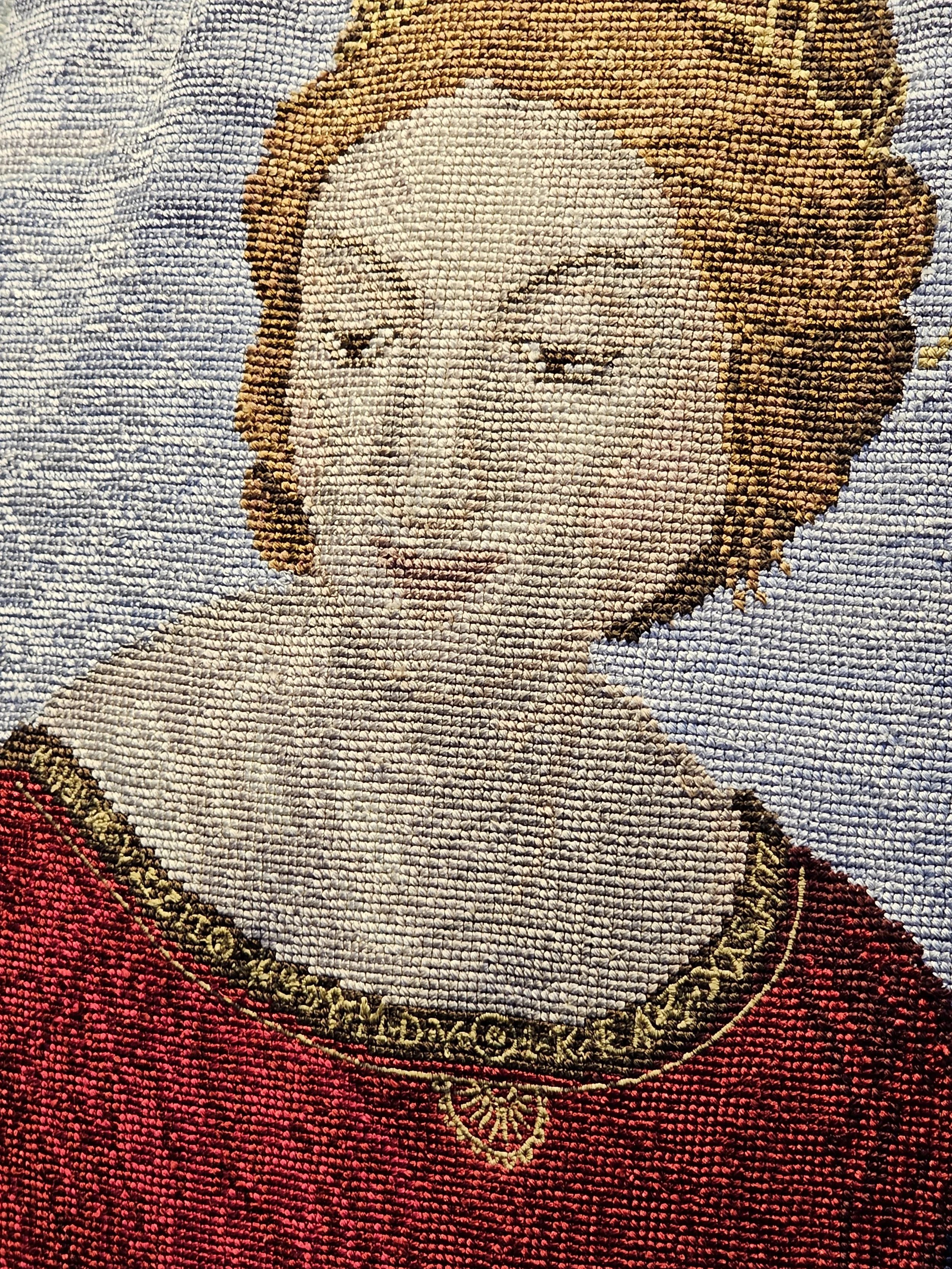 A close up of needlework which is a lady's face