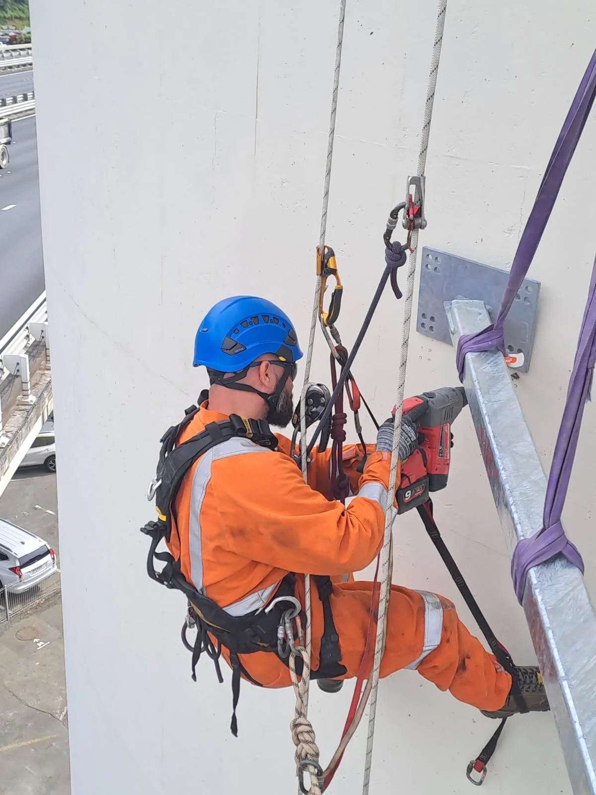 worker on abseil ropes drilling into a building