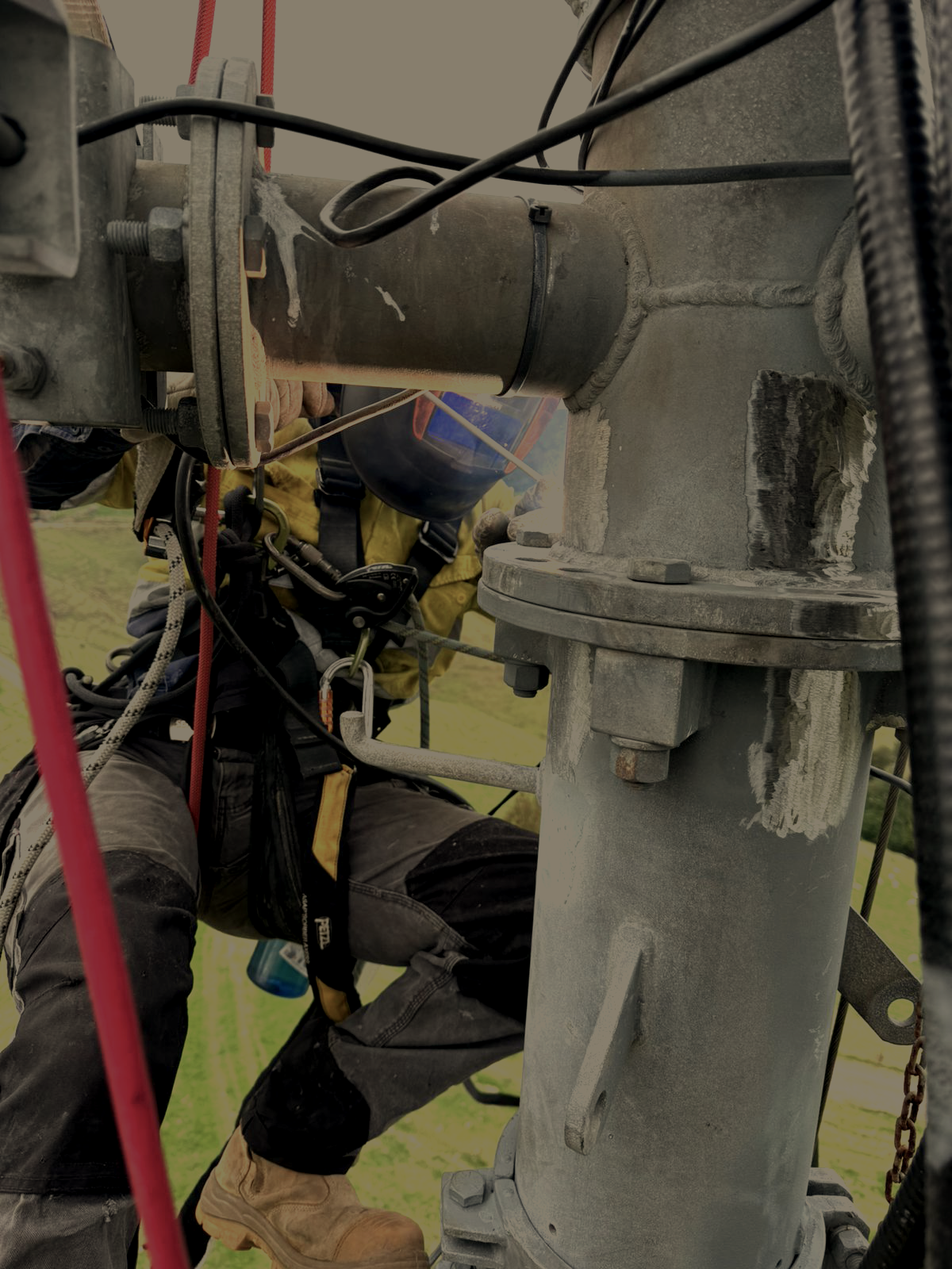 man in welding mask on climbing ropes weding a large steel join