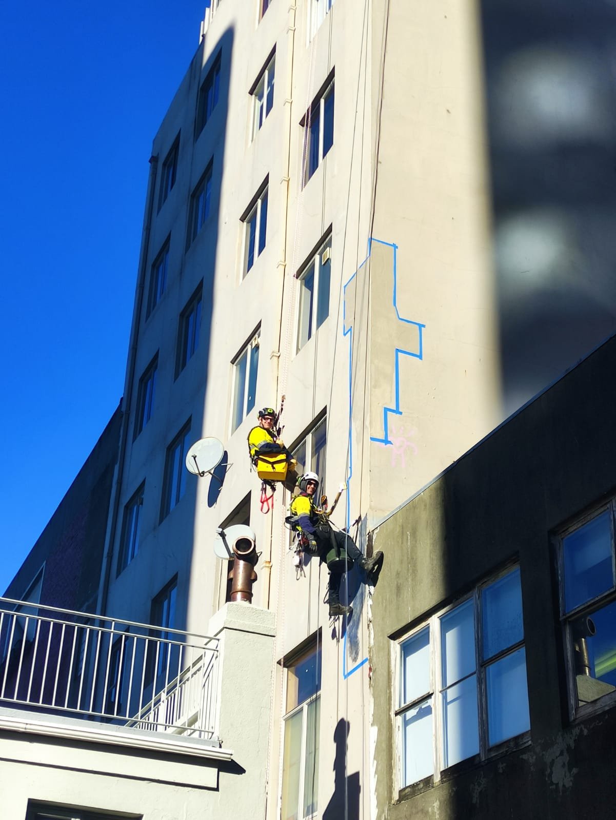 men abseiling on ropes fixing a leak