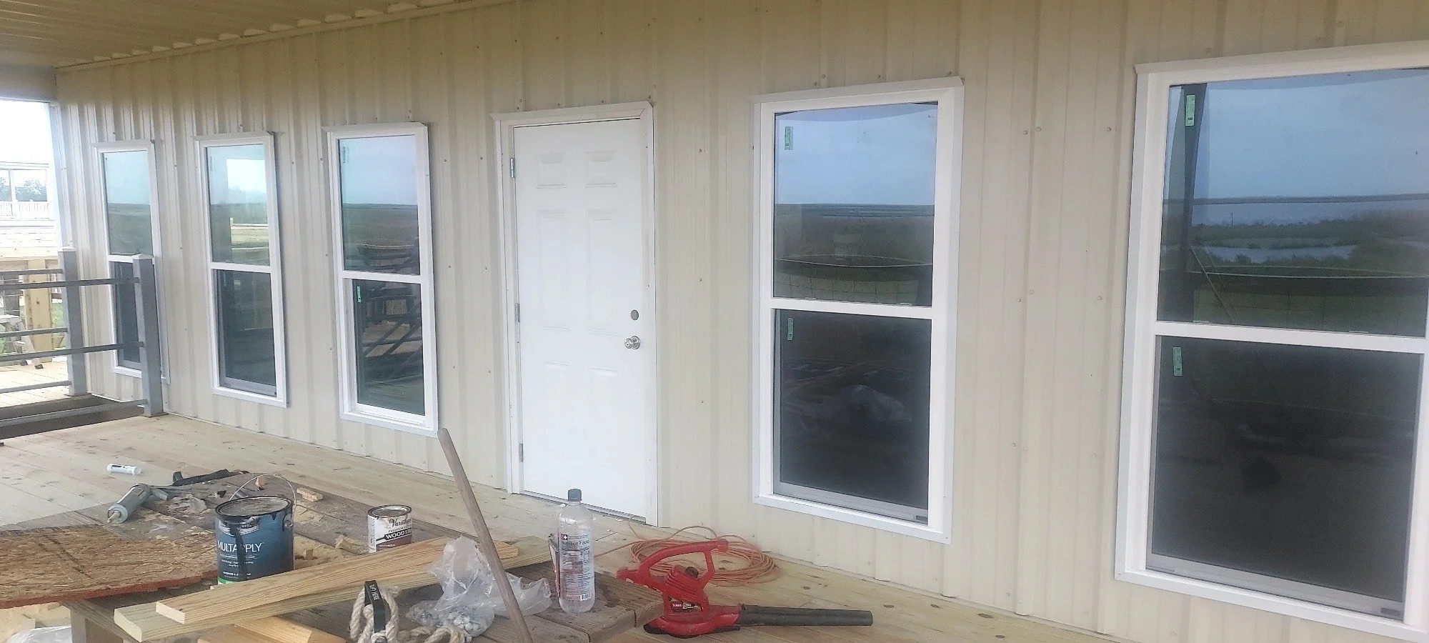 Front porch of raised camp. Windows, corrugated metal walls and roof. (2-4)