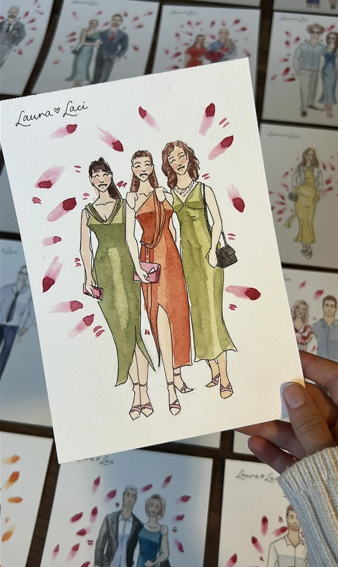 Hand-drawn illustration of three women in formal dresses, holding small purses, surrounded by pink flower petals, with the names Laura and Laci written at the top left.