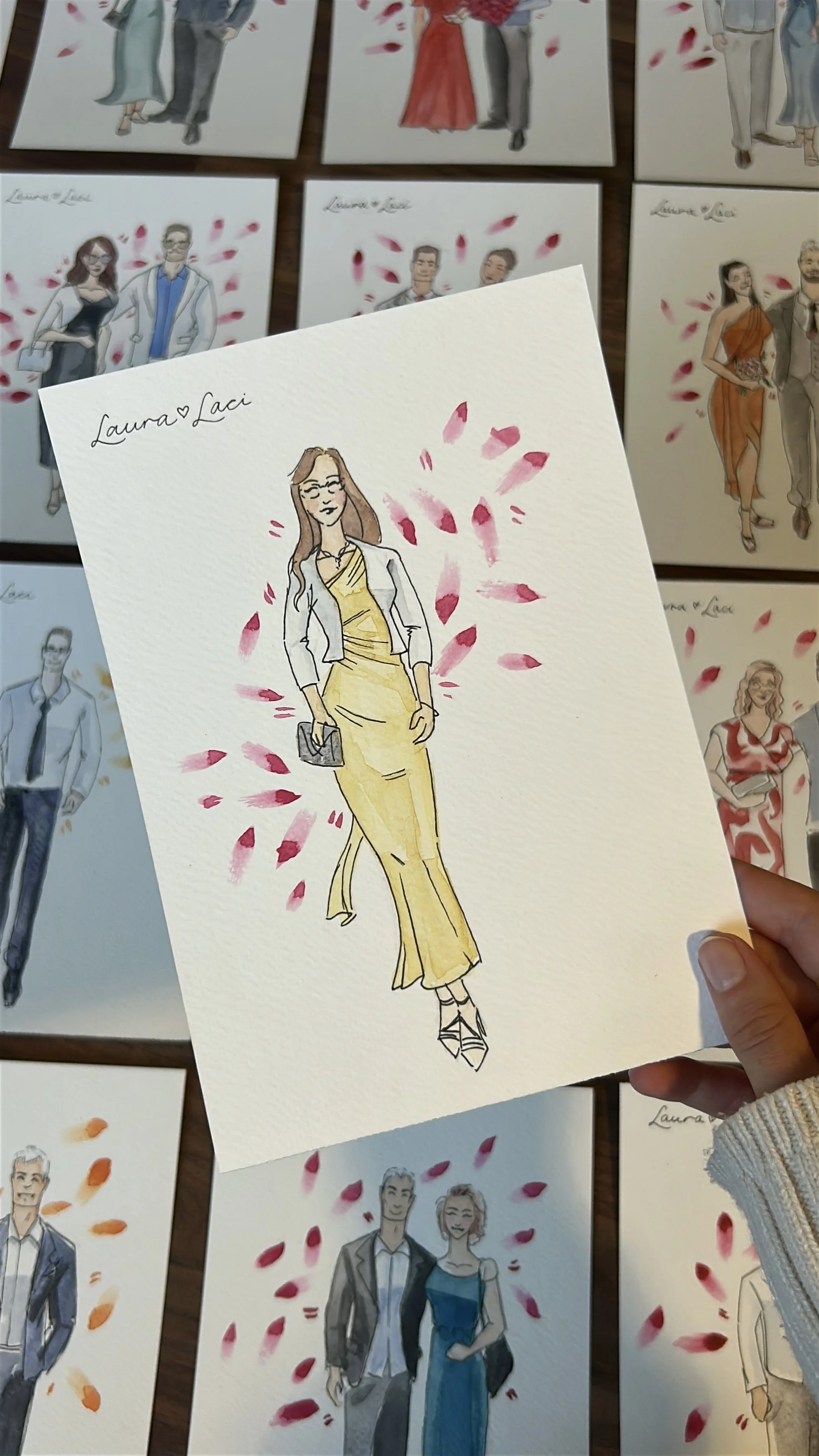 Watercolor illustration of a woman in a yellow dress with a blazer, holding a clutch, surrounded by pink petals, with "Laura Laci" handwritten at the top left.