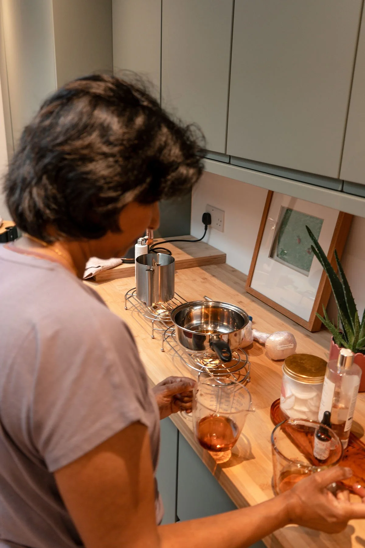 Preparing warm herbal oil for Ayurvedic treatment in West London studio