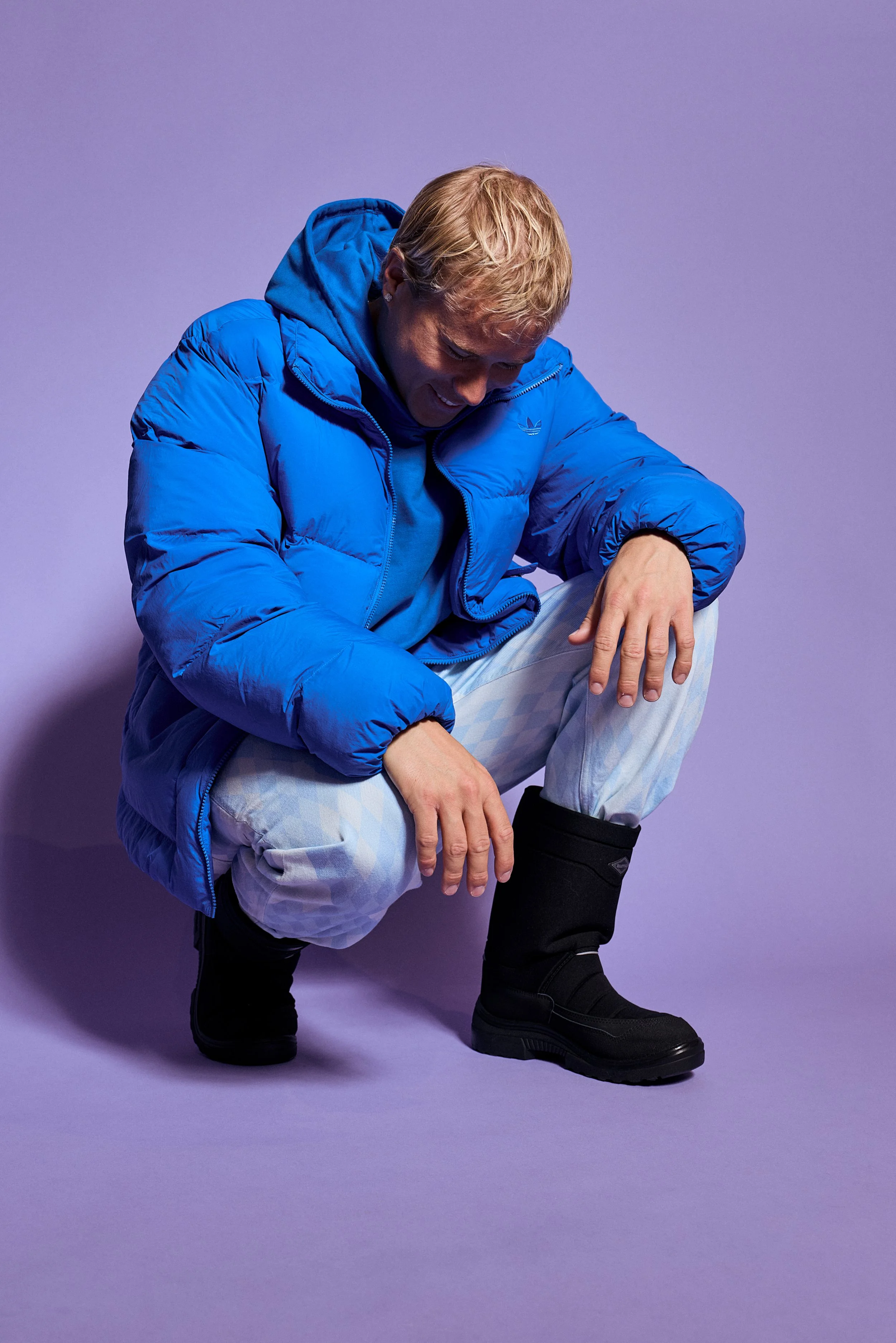 Jaakko Parkkali hymyilee kyykyssä Kuoman mustat kengät jalassa.