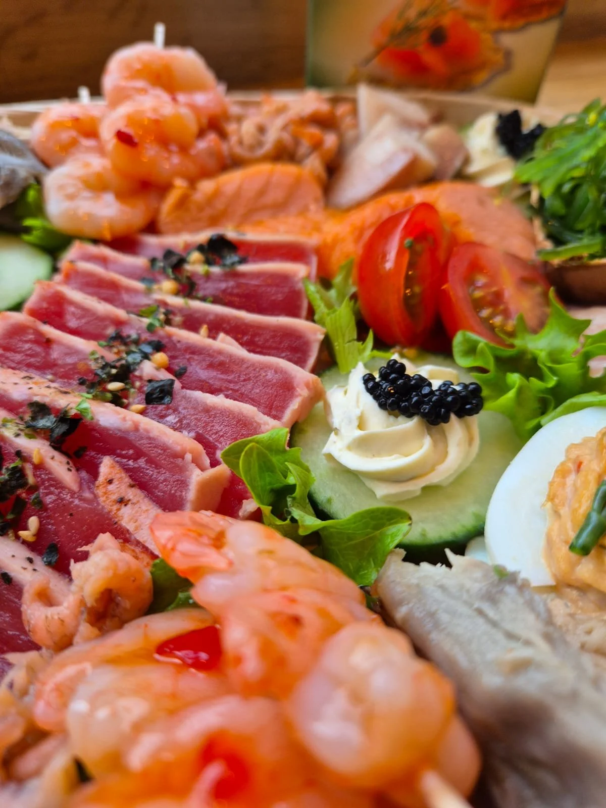 Close-up van een kleurrijke vlees- en garnalensalade met tomaat, komkommer, ei en andere ingrediënten.