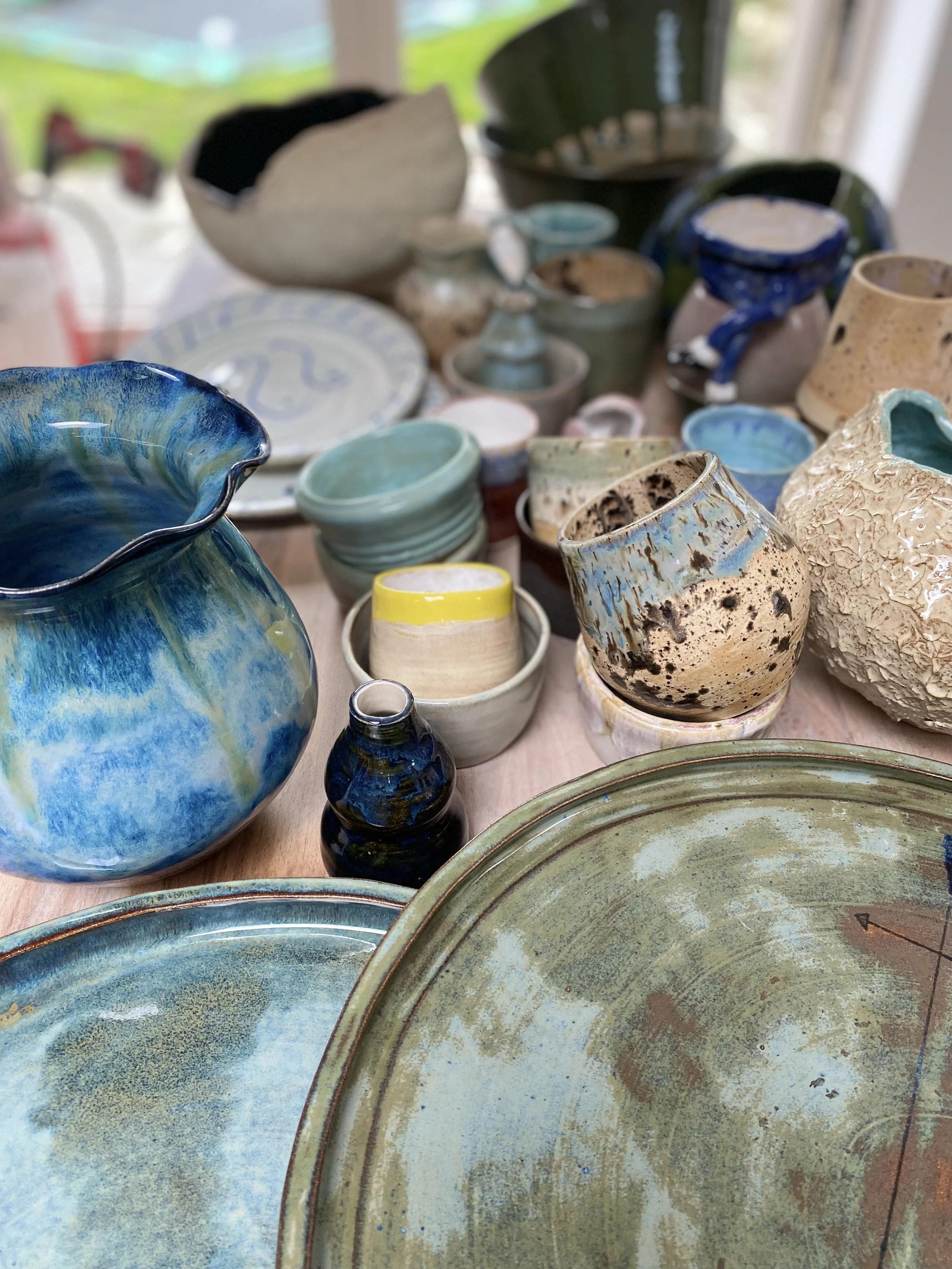 A collection of various ceramic pottery and dishes, including bowls, vases, and plates, arranged on a table.