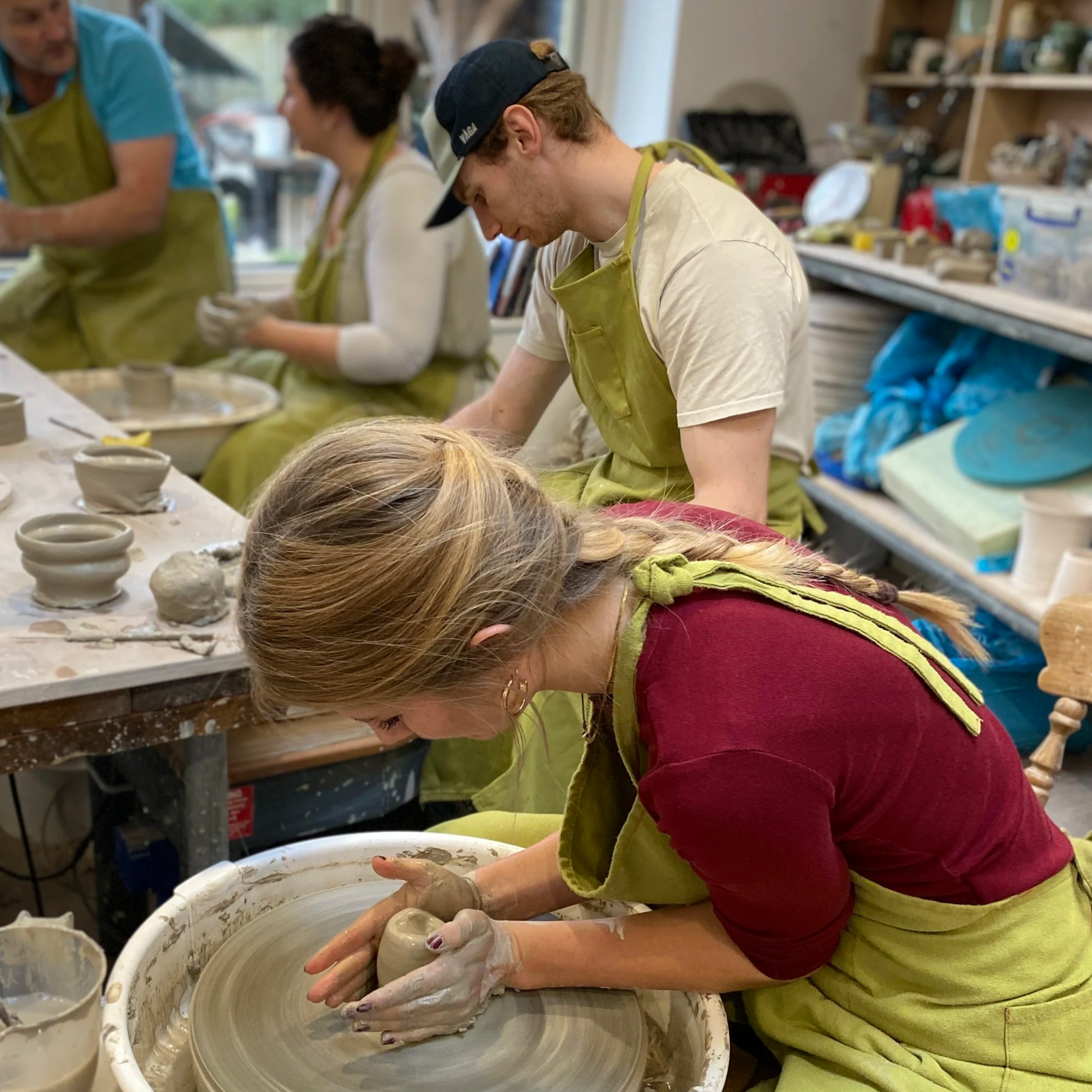 People in a pottery class shaping clay on a pottery wheel.