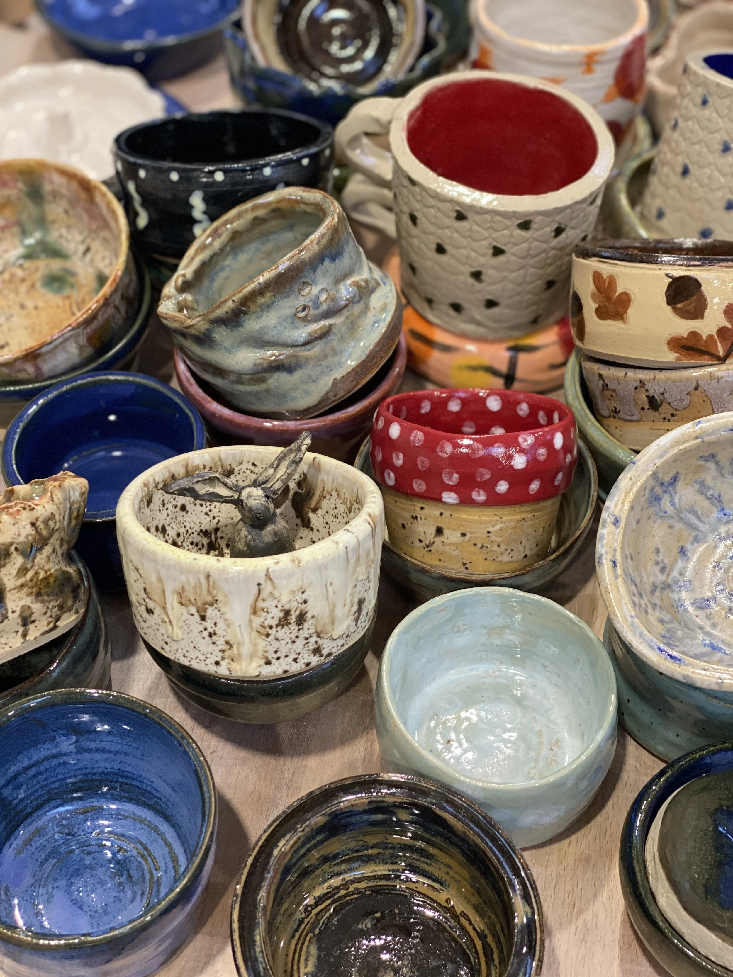 A collection of colorful handmade pottery cups with various patterns and textures.