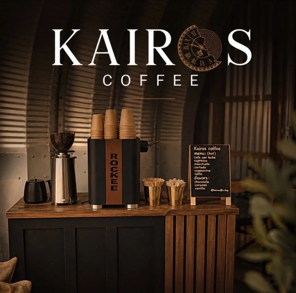 Interior of Kairos Coffee shop featuring a coffee station with disposable cups, ground coffee, and a menu board listing hot coffee options and flavors.