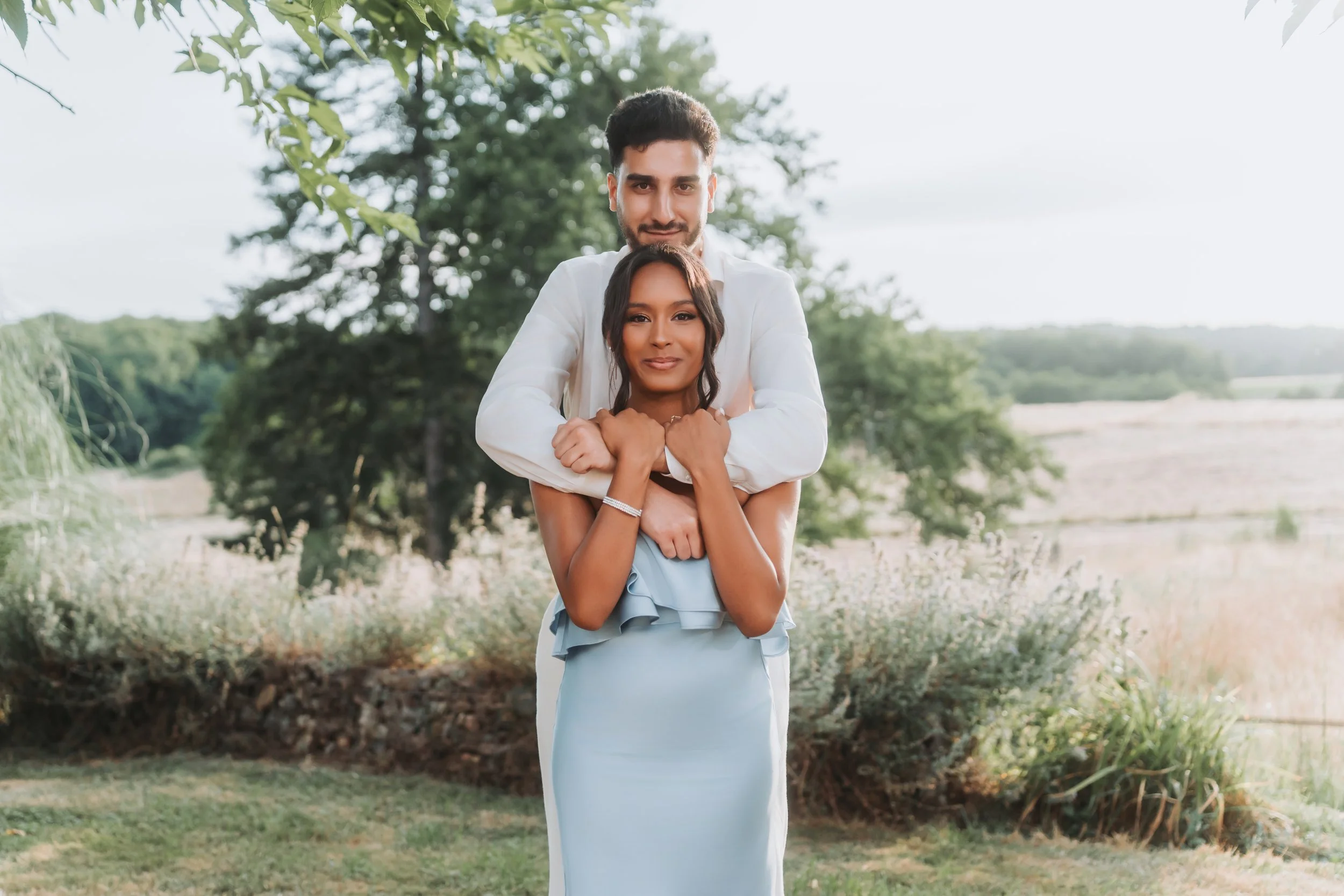 Un homme et une femme posent ensemble dans un jardin en plein air.