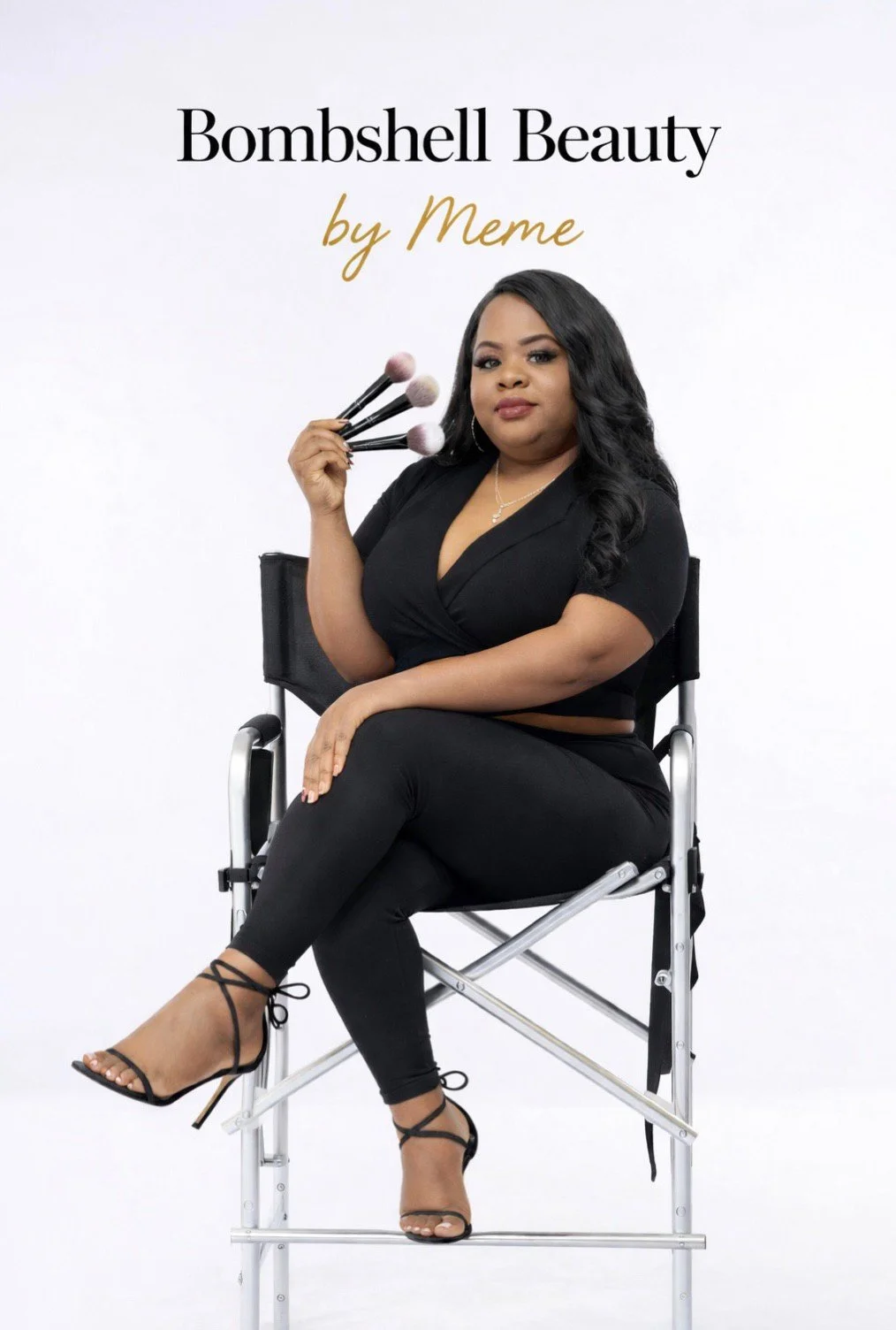 A woman seated on a director's chair holding makeup brushes, with text that reads 'Bombshell Beauty by Meme' in a studio setting.