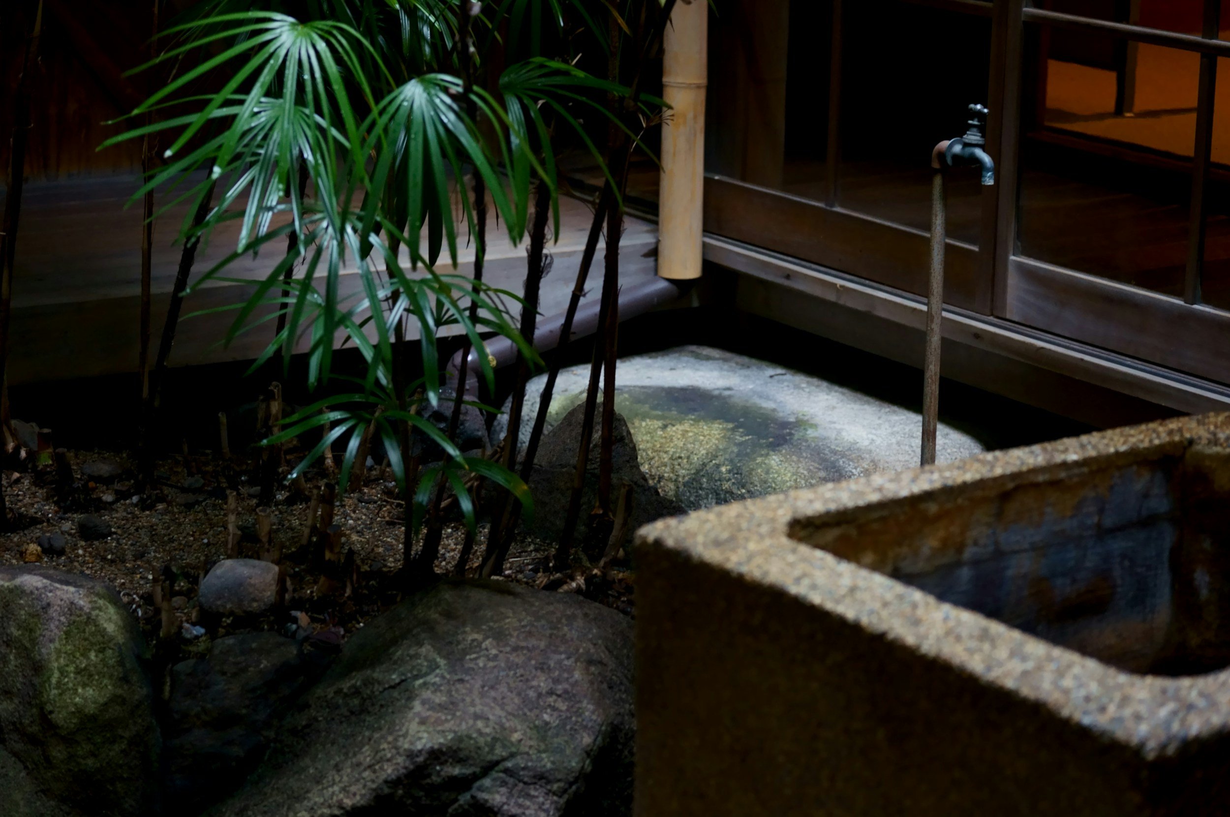 a close up of a onsen bathtub outside beside rocks and some plants