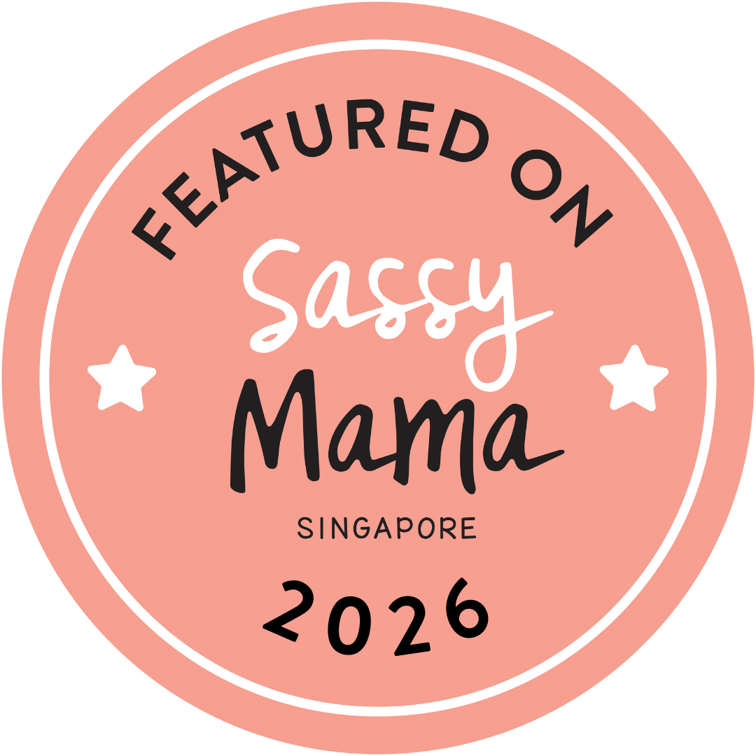 Pink circular sticker with black and white text that reads: 'Featured on Sassy Mama Singapore 2026' with two small white stars.