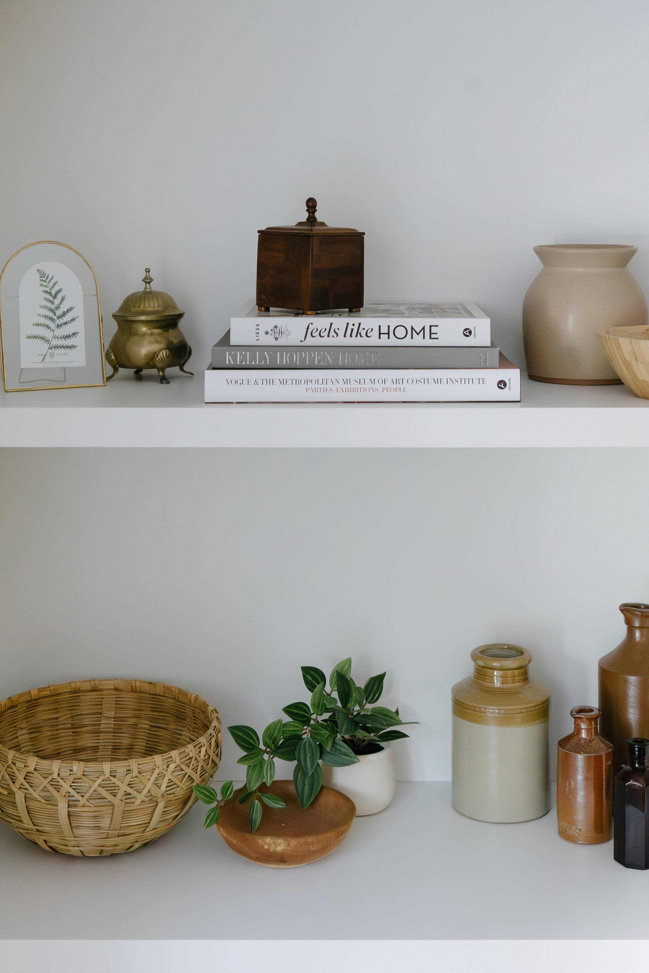Decorative shelves with various vases, bowls, a wicker basket, a small plant, and books.