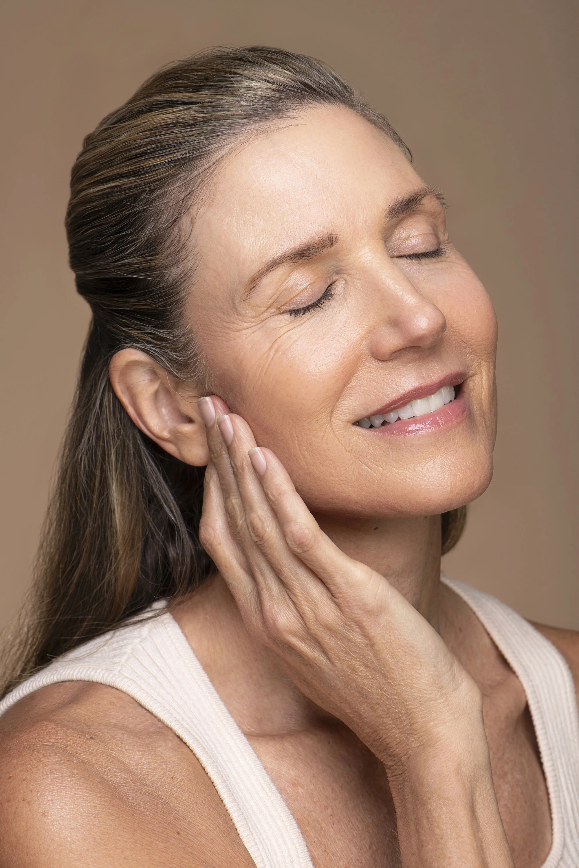  Commercial skincare portrait photography by Atlanta beauty photographer Caitlin Tabilog for AYA Skin, featuring a female Forward The Agency model against a white and beige seamless studio backdrop with natural skin texture and clean beauty styling. 