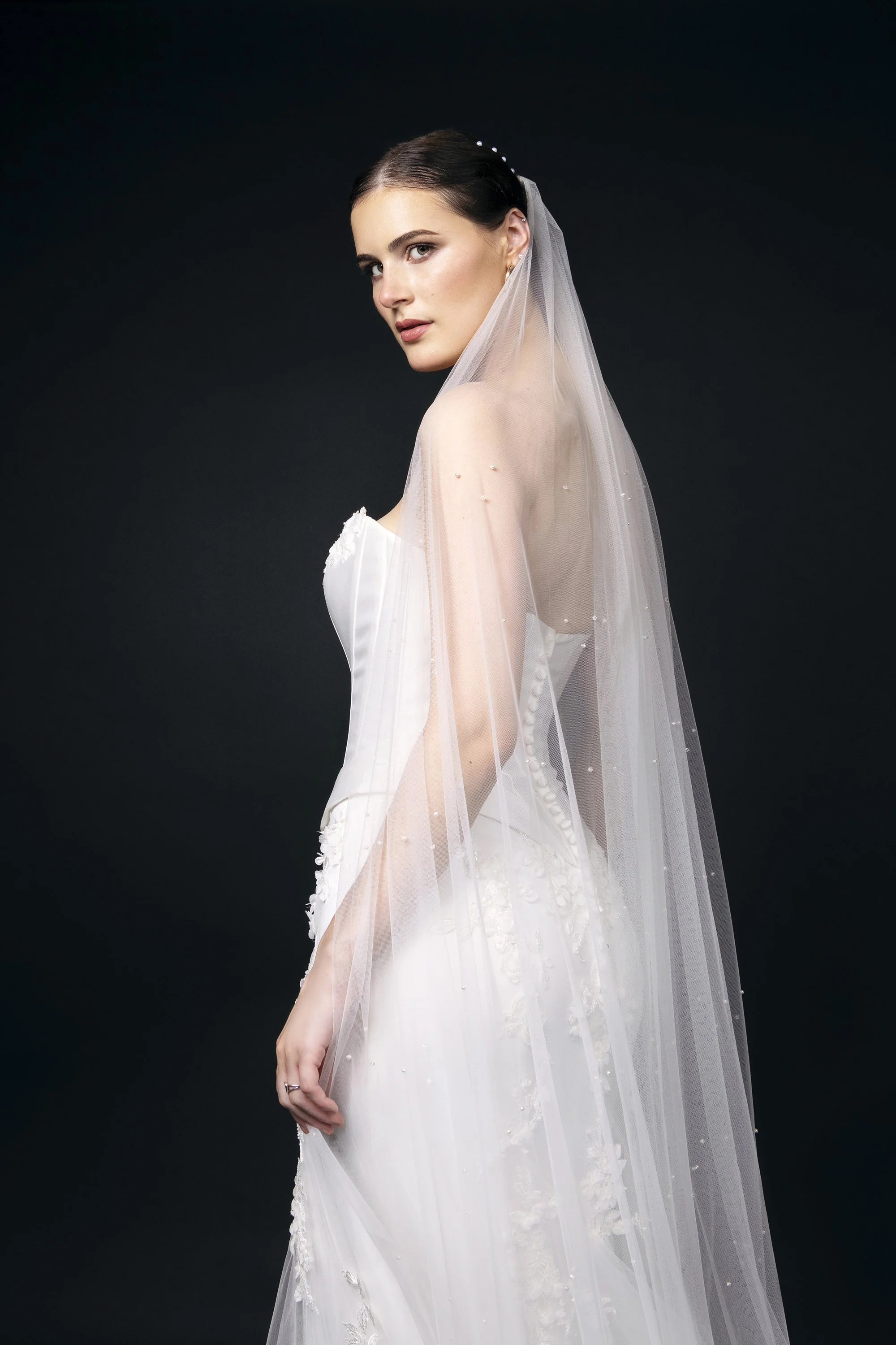 Editorial bridal fashion photography featuring Forward The Agency model Sabrina wearing an Anna Christine Bridal wedding dress from Canton, Georgia, photographed by Caitlin Tabilog against a dramatic black background, with bridal hair by Golden Hair 
