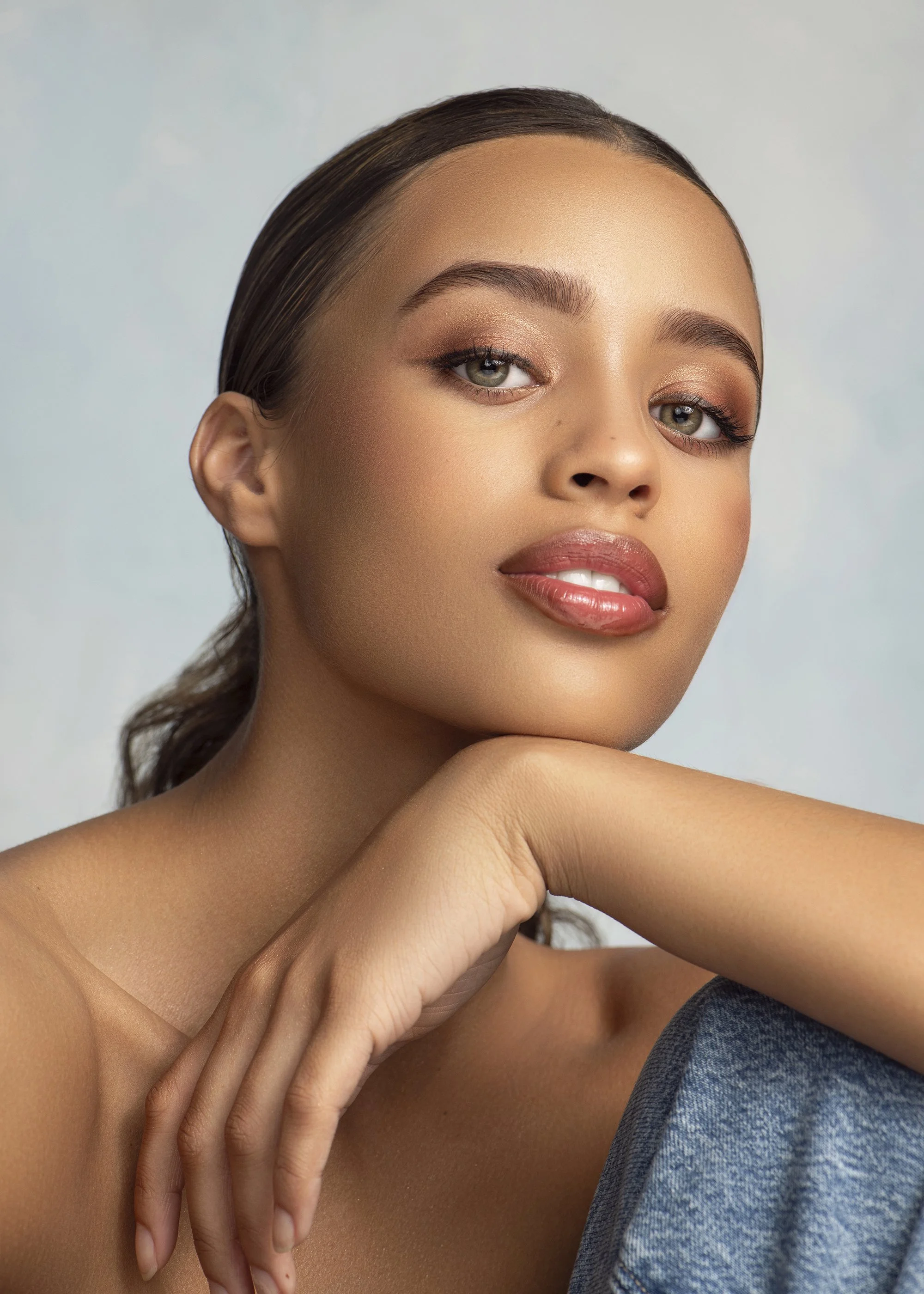 Commercial beauty portrait created at Industry Makeup Academy in Atlanta, Georgia, featuring a Forward The Agency model with flawless makeup, soft studio lighting, and a hand-painted blue backdrop. Luxury beauty, fashion, and portrait photography by 