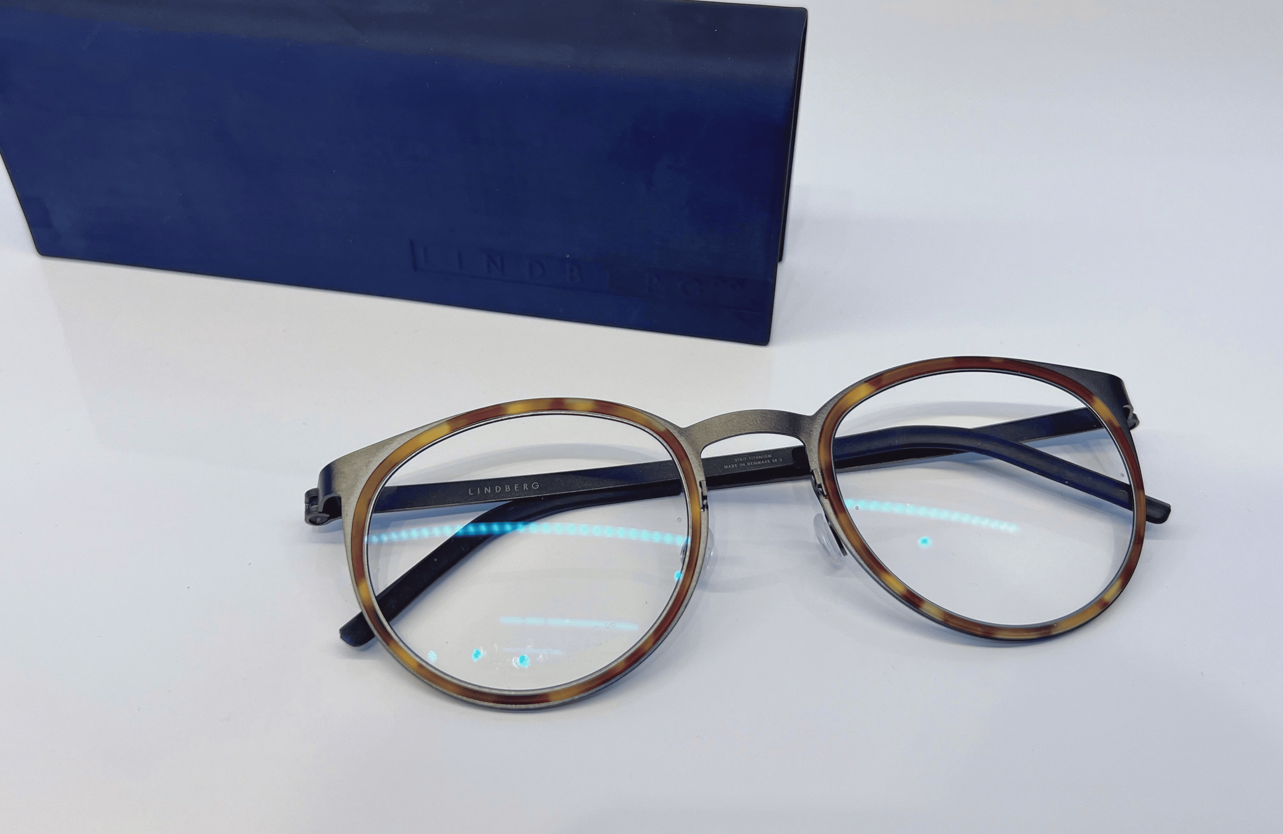 Glasses with tortoiseshell frames and a blue case on a white surface.
