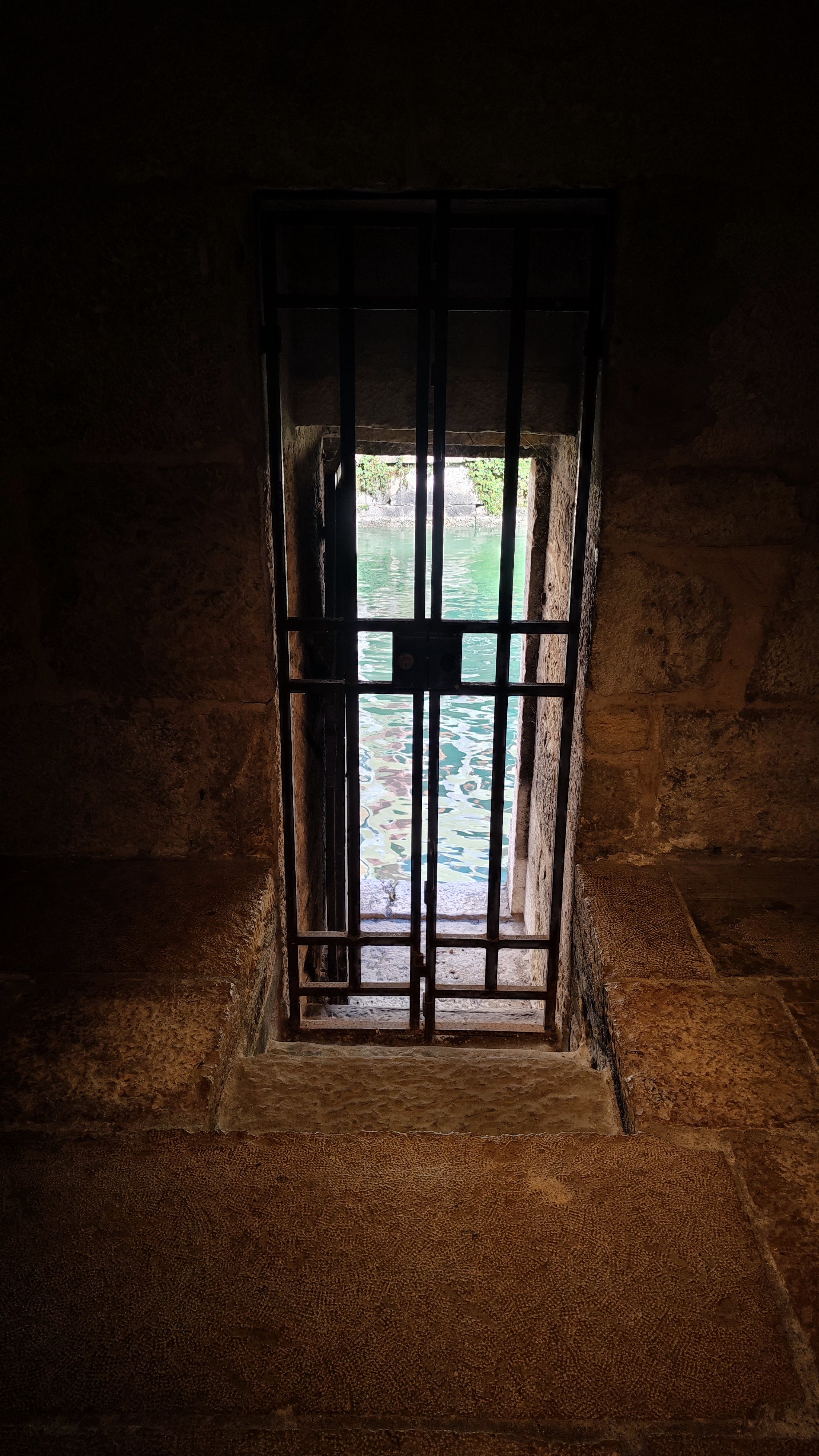 Porte d'un château en ferraille qui donne sur l'eau.