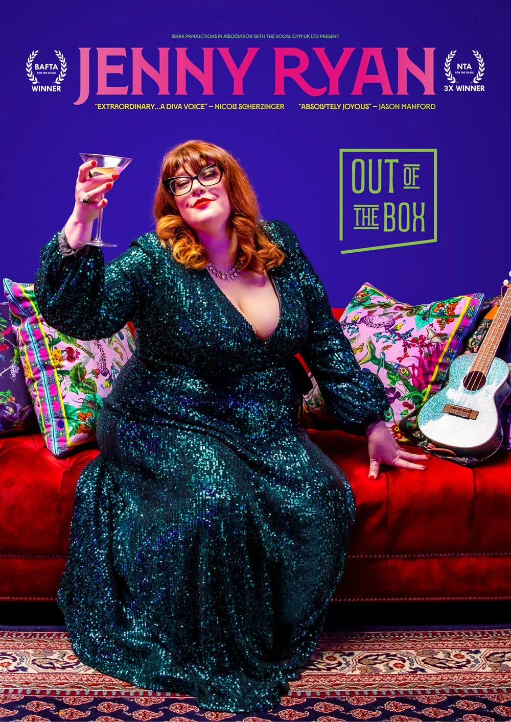 A woman with red hair, glasses, and a sequined dress sitting on a red velvet couch holding a martini glass. Behind her is a vibrant purple wall with posters announcing Jenny Ryan, a musical or theatrical production titled 'Out of the Box,' displaying