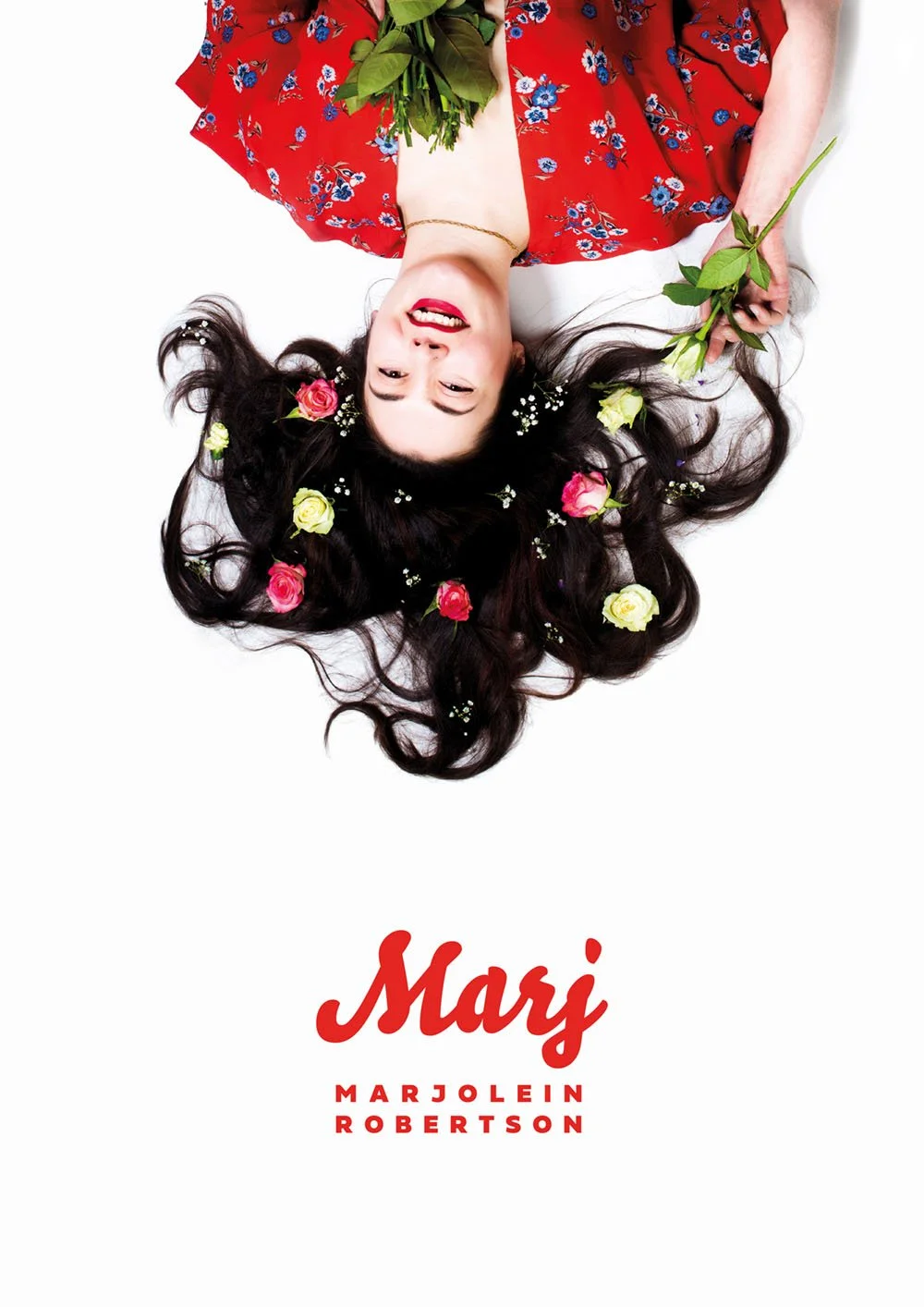 Book cover image with a woman lying down, smiling, with flowers in her long dark hair, holding a rose. She is wearing a red floral dress, and the title "Marj" along with the author's name Marjolein Robertson are written in red text.