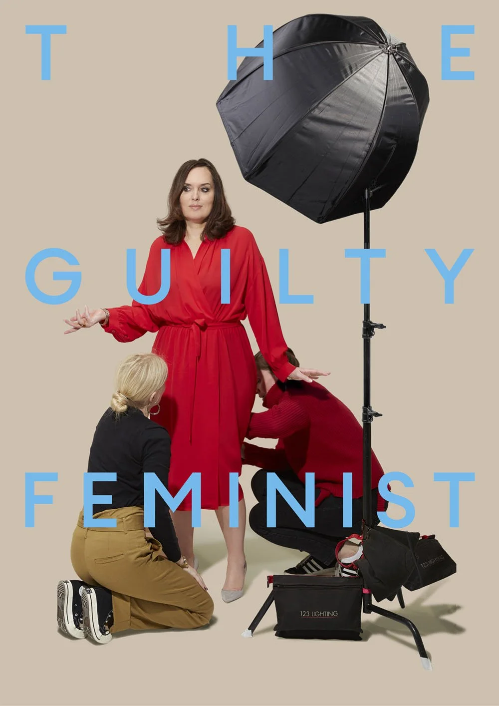 A woman in a red dress standing under a large black umbrella surrounded by two women, one kneeling with blonde hair and the other crouching with dark hair. The background is beige, and blue text overlays read 'The Guilty Feminist'.