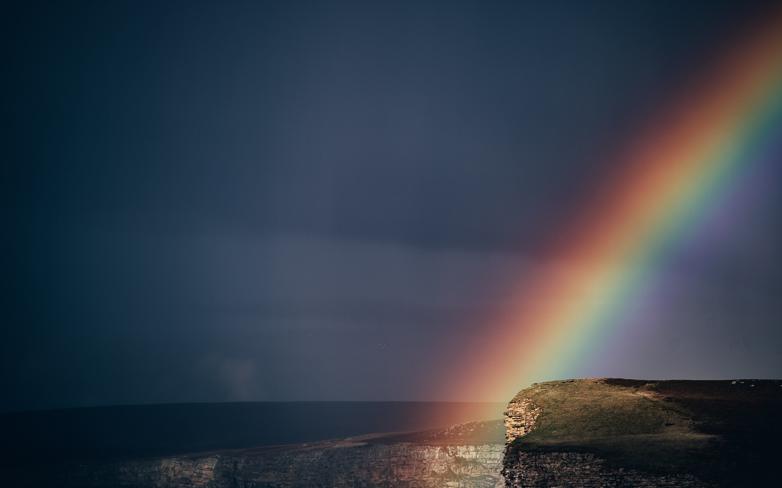 Rainbow catching a cliff by the sea