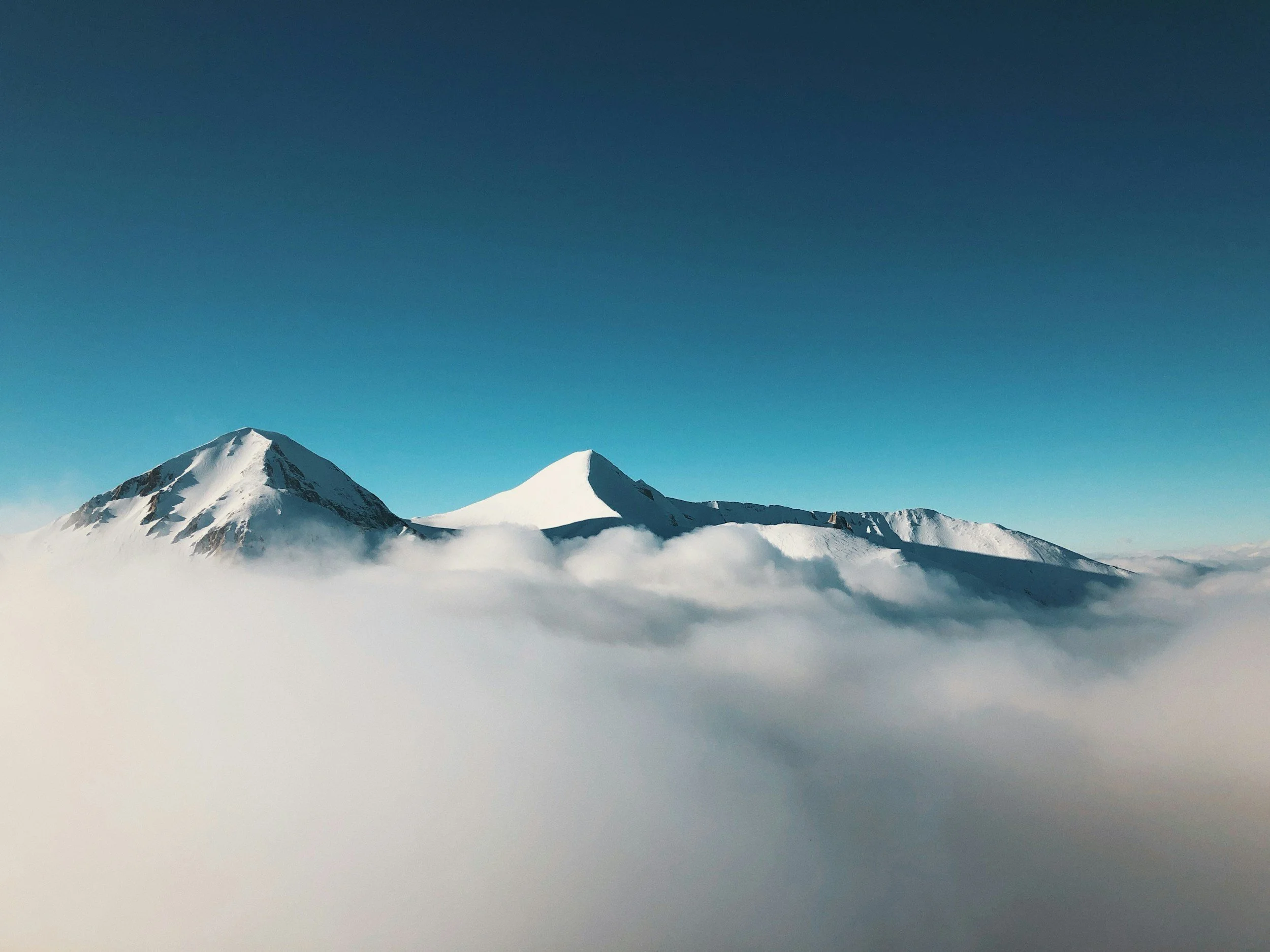 [Image Description: Snow-capped mountains with a clear blue sky in the background.]