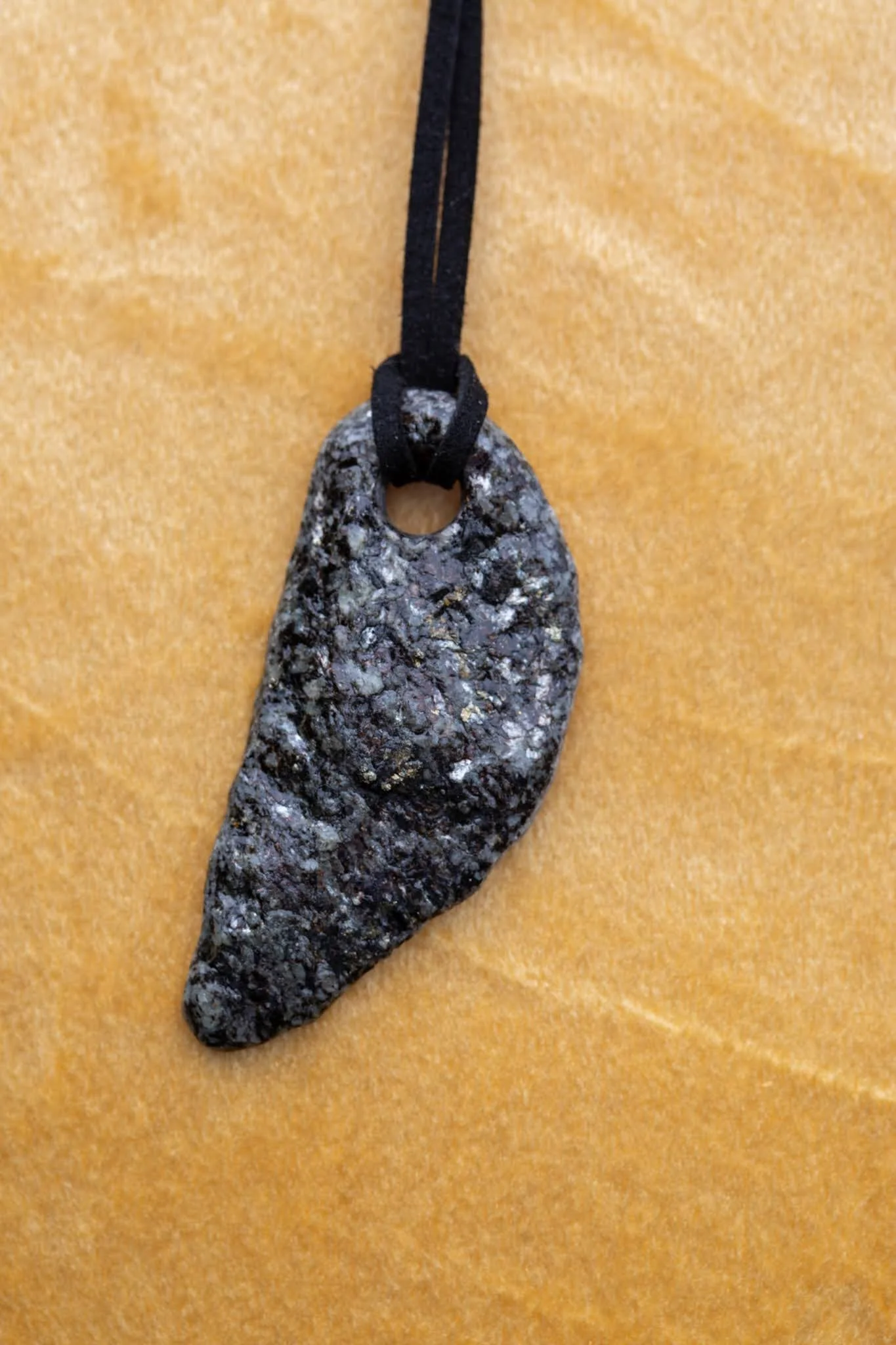 Black Anjy's Eye necklace against gold pillow