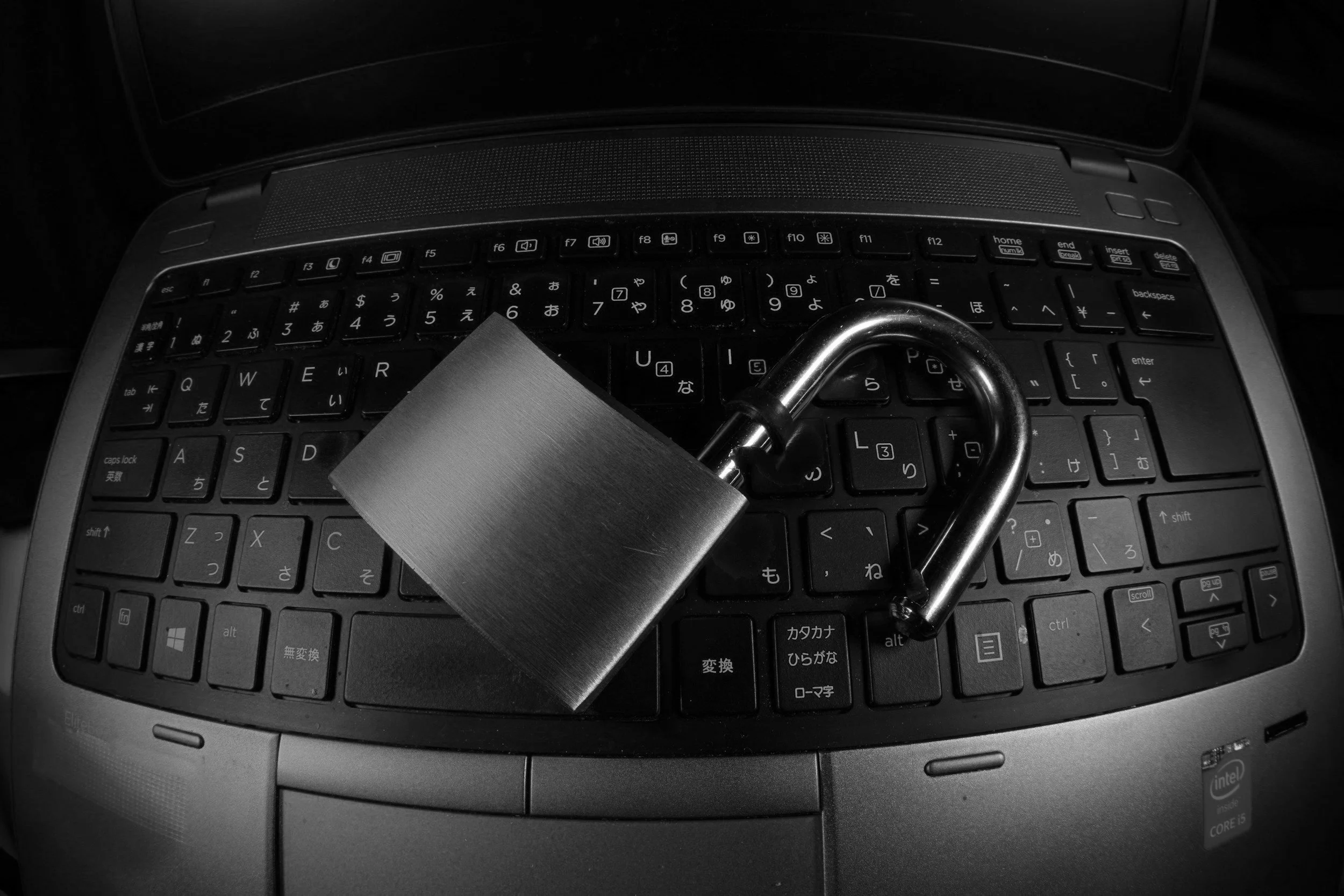 A laptop keyboard with a silver padlock and a U-shaped lock placed on top.