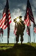 Soldier standing in front of US flags at sunset