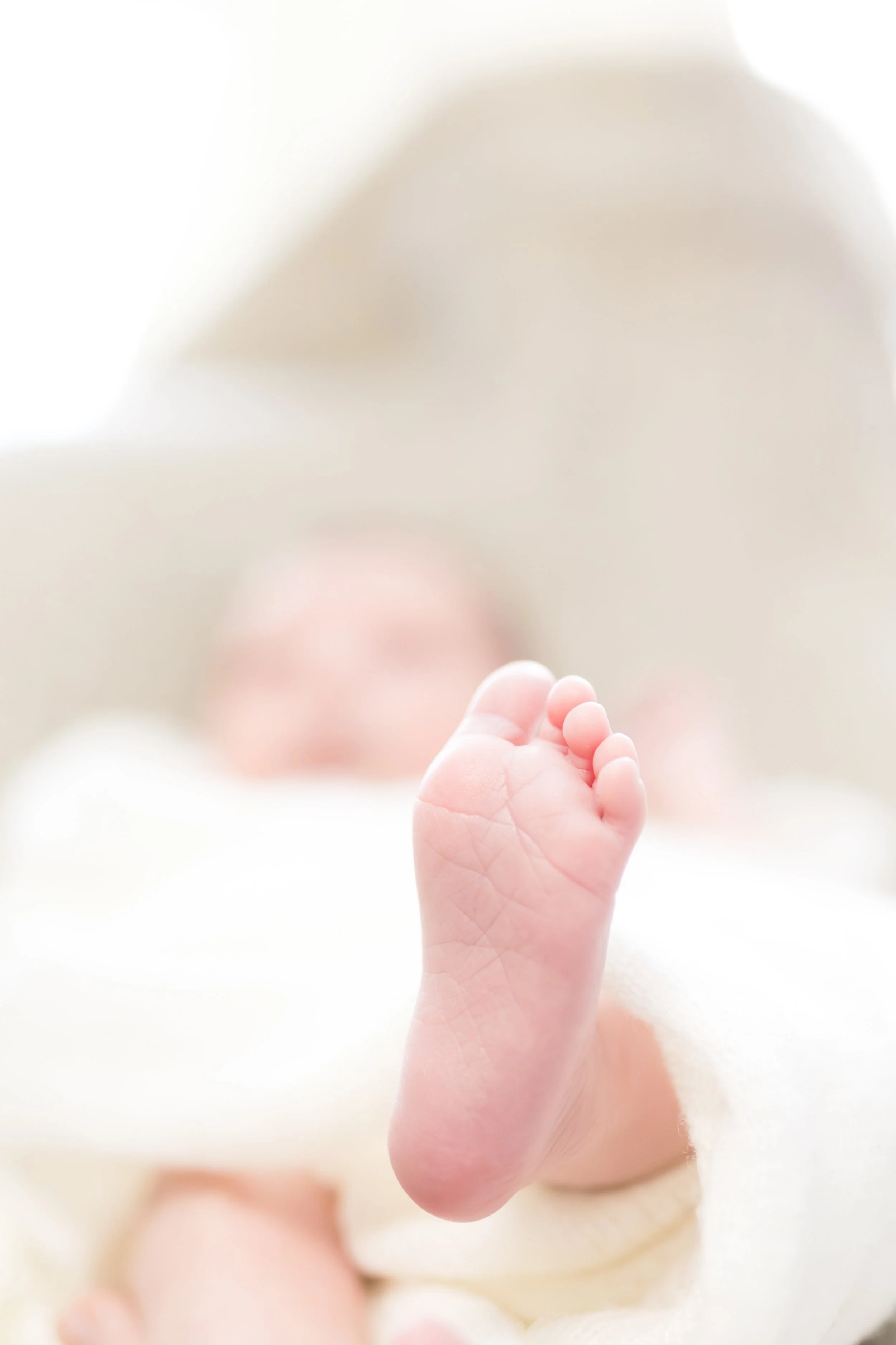 Nahaufnahme eines kleinen Baby-Füsschens, das auf einem weichen, weißen Tuch liegt.