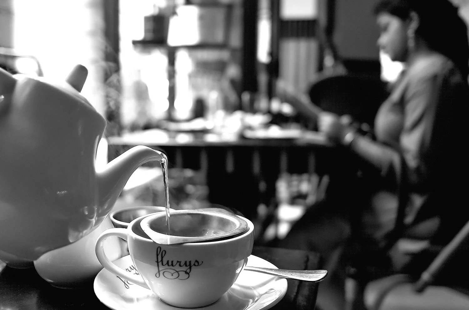 Traditional Darjeeling tea being poured from a teapot into a cup inside a café.
Kolkata