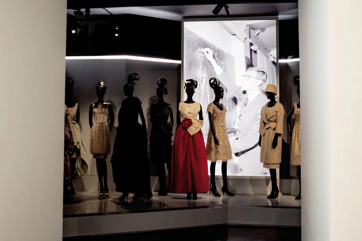 A display of Dior couture unfolds before an image of the designer at work, linking the garments to their creative origin.