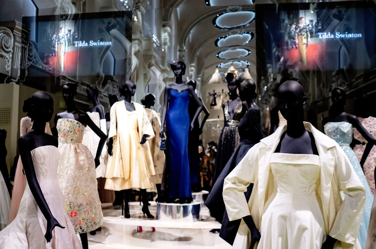 The architectural design of the exhibition frames the garments, emphasizing the relationship between space and couture.
