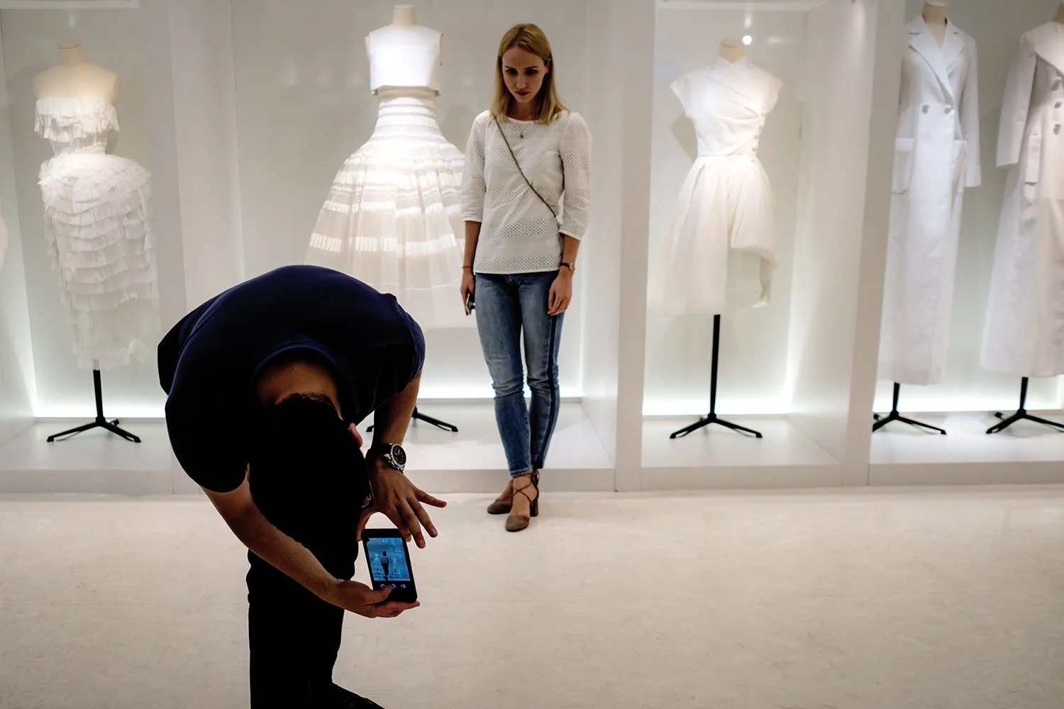 A companion bends to capture a photograph for her beside the Dior display.