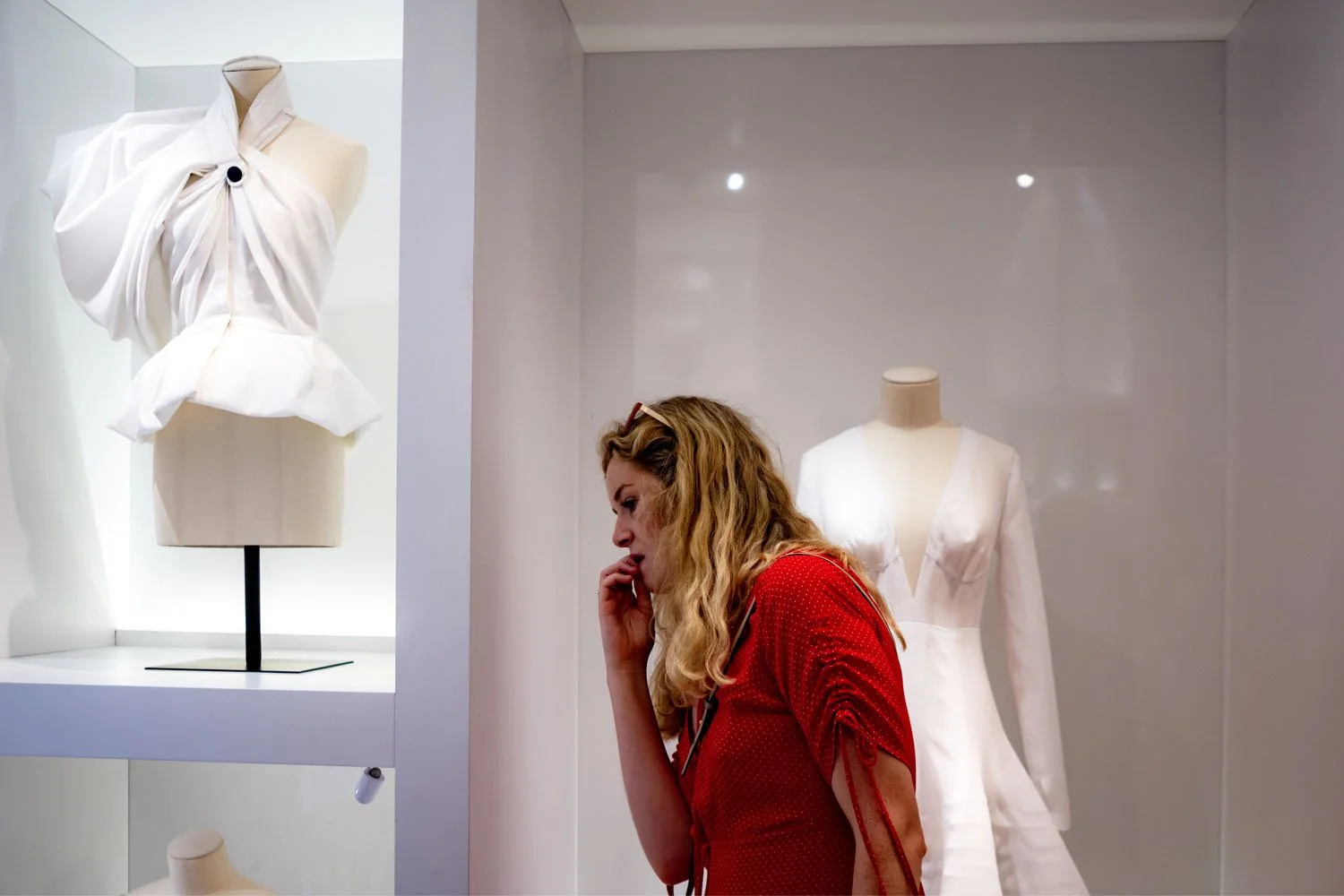 A visitor quietly observes a Dior garment, a moment of personal contemplation within the exhibition.