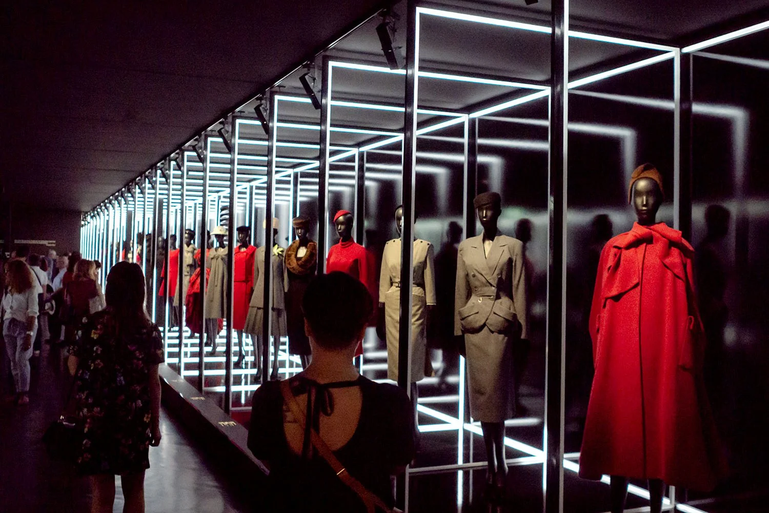 Dior silhouettes extend through the illuminated corridor, resembling a runway frozen within the museum space.