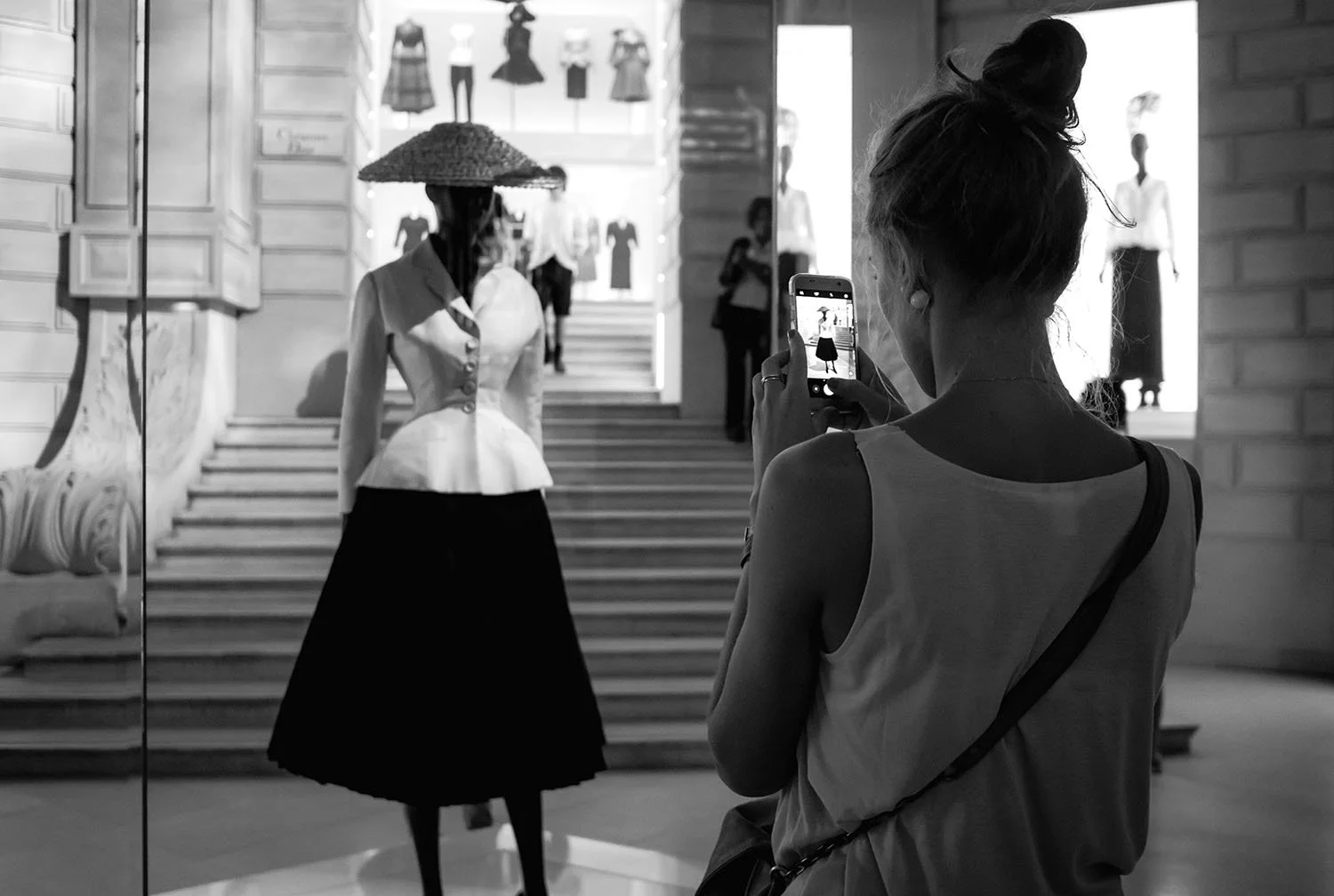 Installed at the entrance of the exhibition, Dior couture draws visitors to photograph themselves with the display, momentarily placing their own presence within the world of fashion.