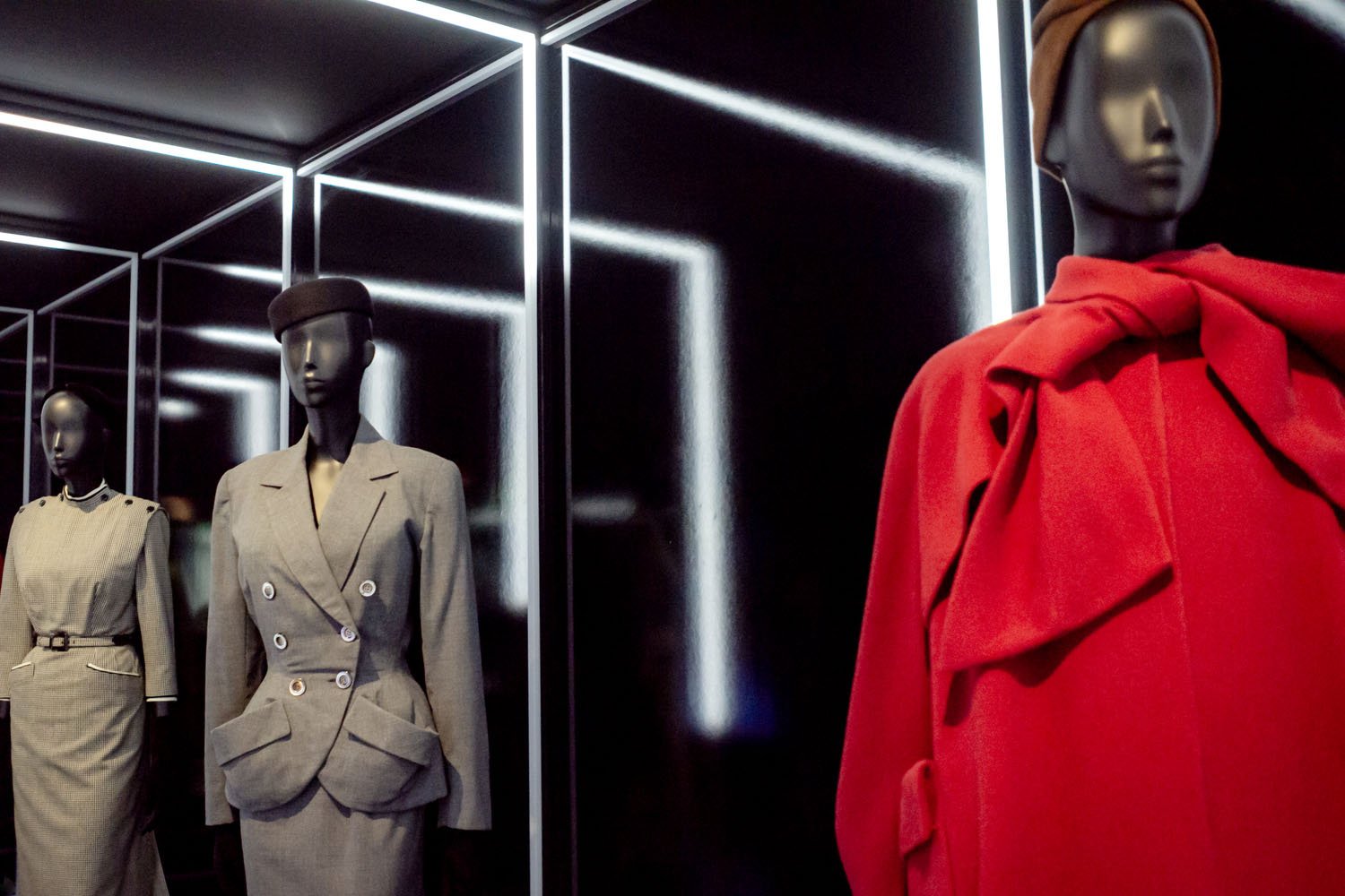 Mannequins wearing Dior designs appear in succession within illuminated frames, where the vivid red coat draws immediate attention.