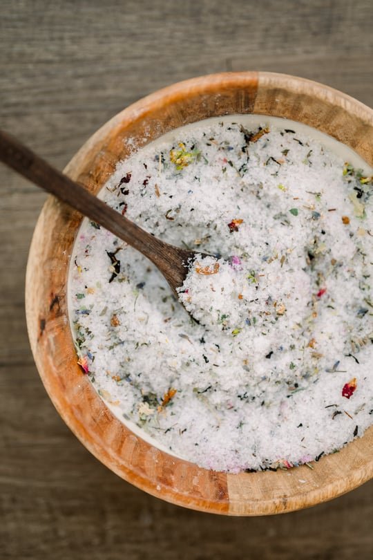 A bowl of mineral bath salts flecked with dried flowers