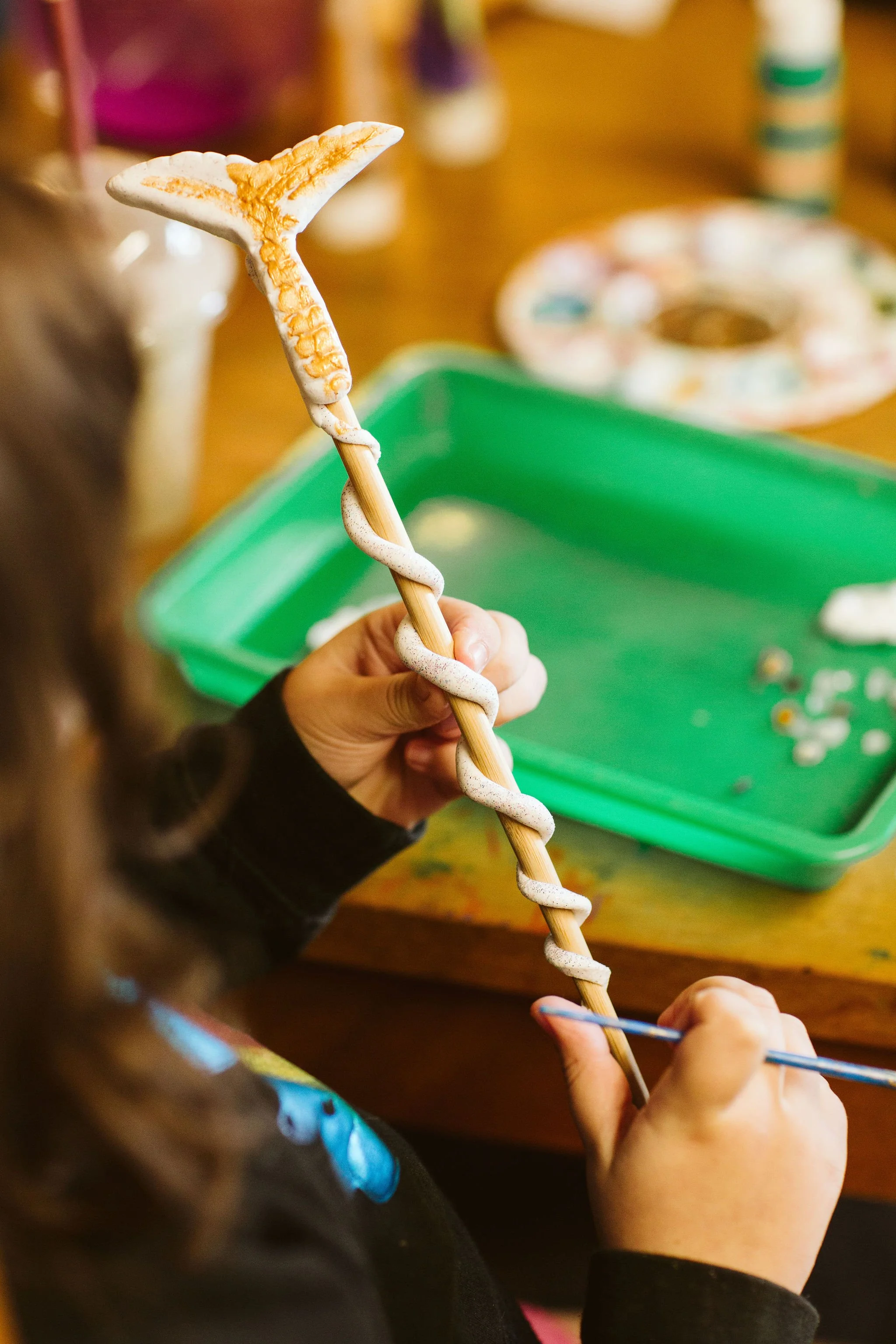 A child painting a mermaid magic wand.