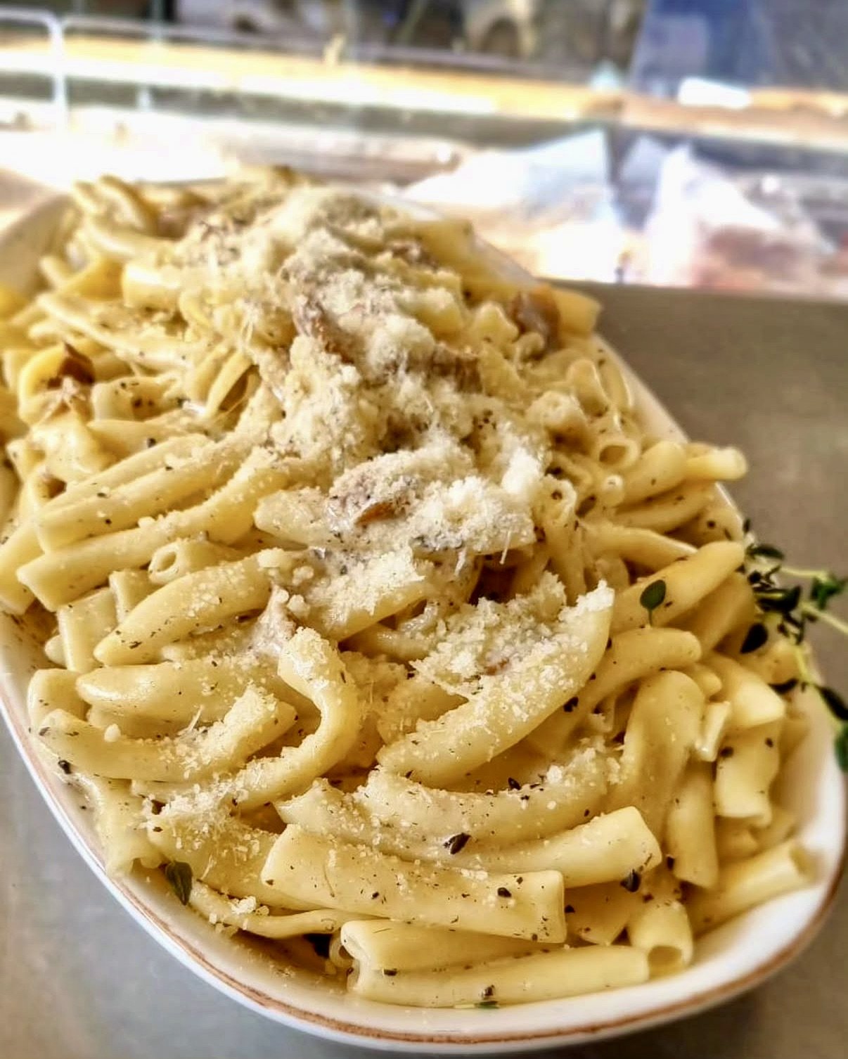 Close-up of a bowl of al dente pasta topped with grated cheese and herbs.